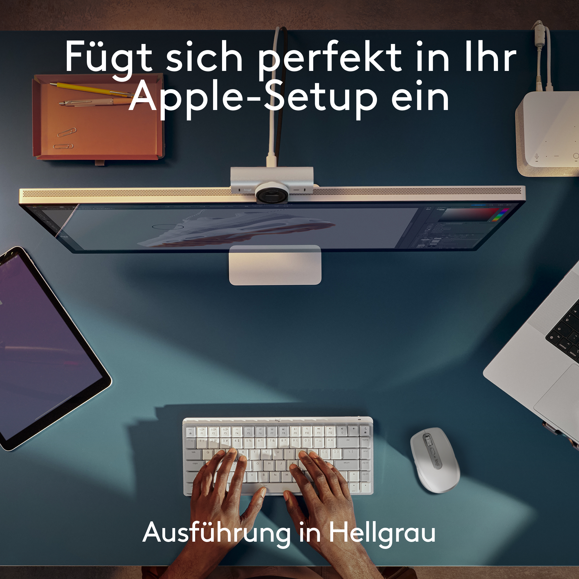 Ein modernes Schreibtisch-Setup mit Monitor, Tastatur, Maus, Tablet und Laptop. Hände auf der Tastatur.