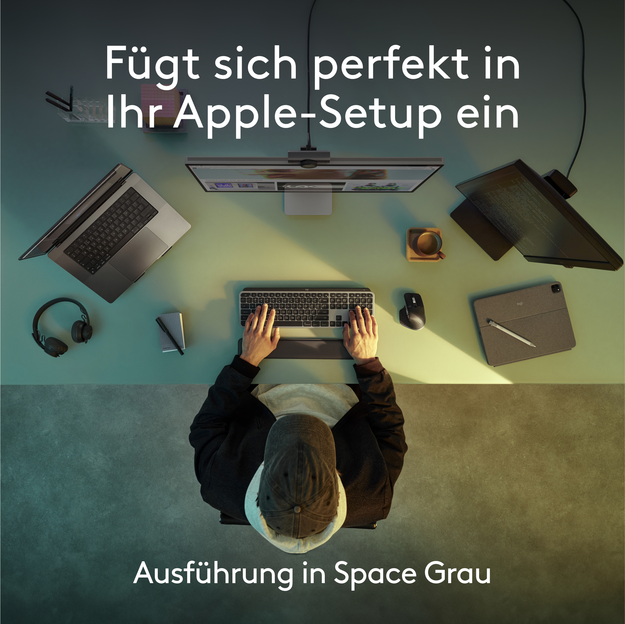 Draufsicht auf einen Schreibtisch. Laptop, Monitor, Tastatur, Maus und Hände einer Person sichtbar.