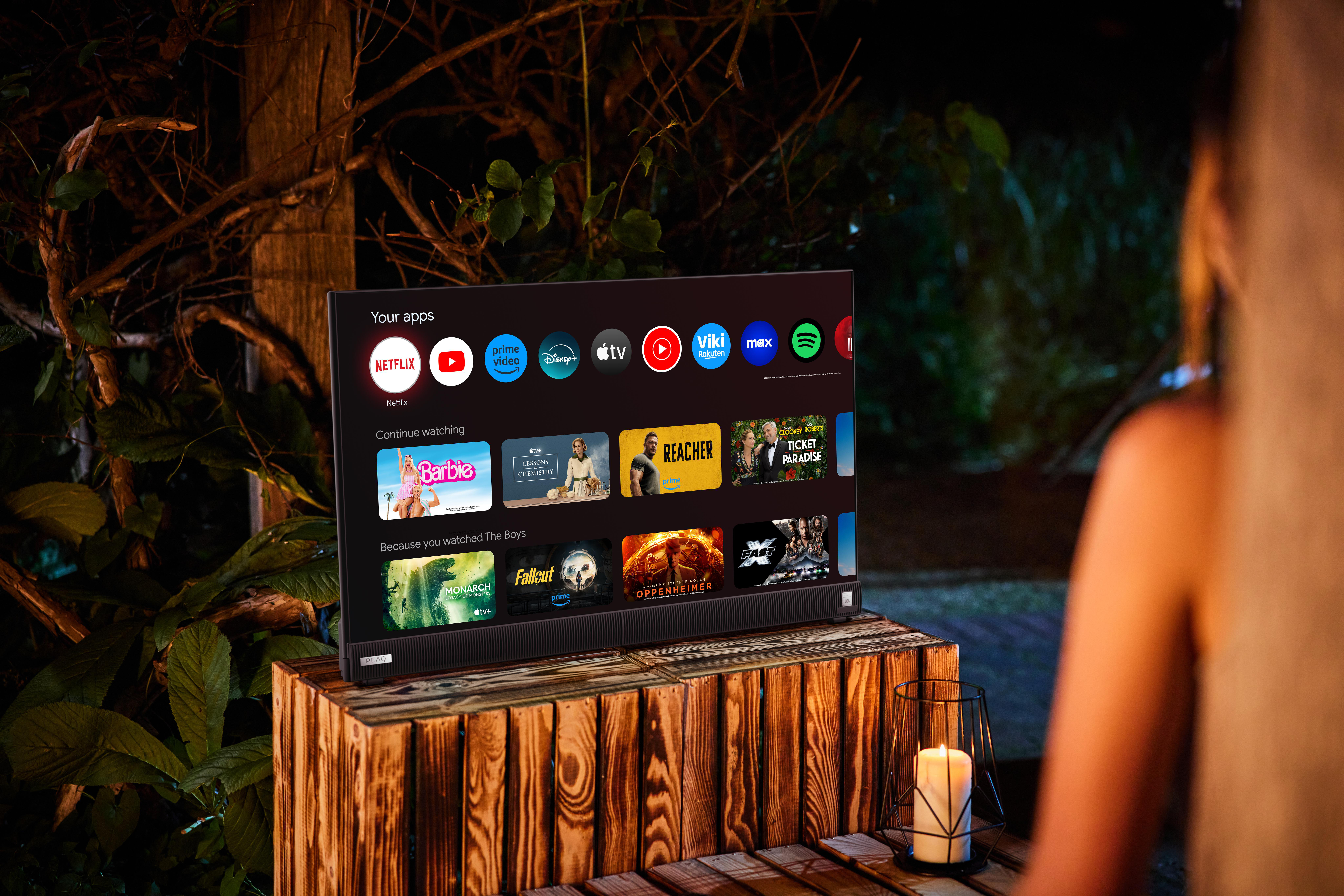 Fernseher auf Holzständer, zeigt Streaming-Apps, im Freien.