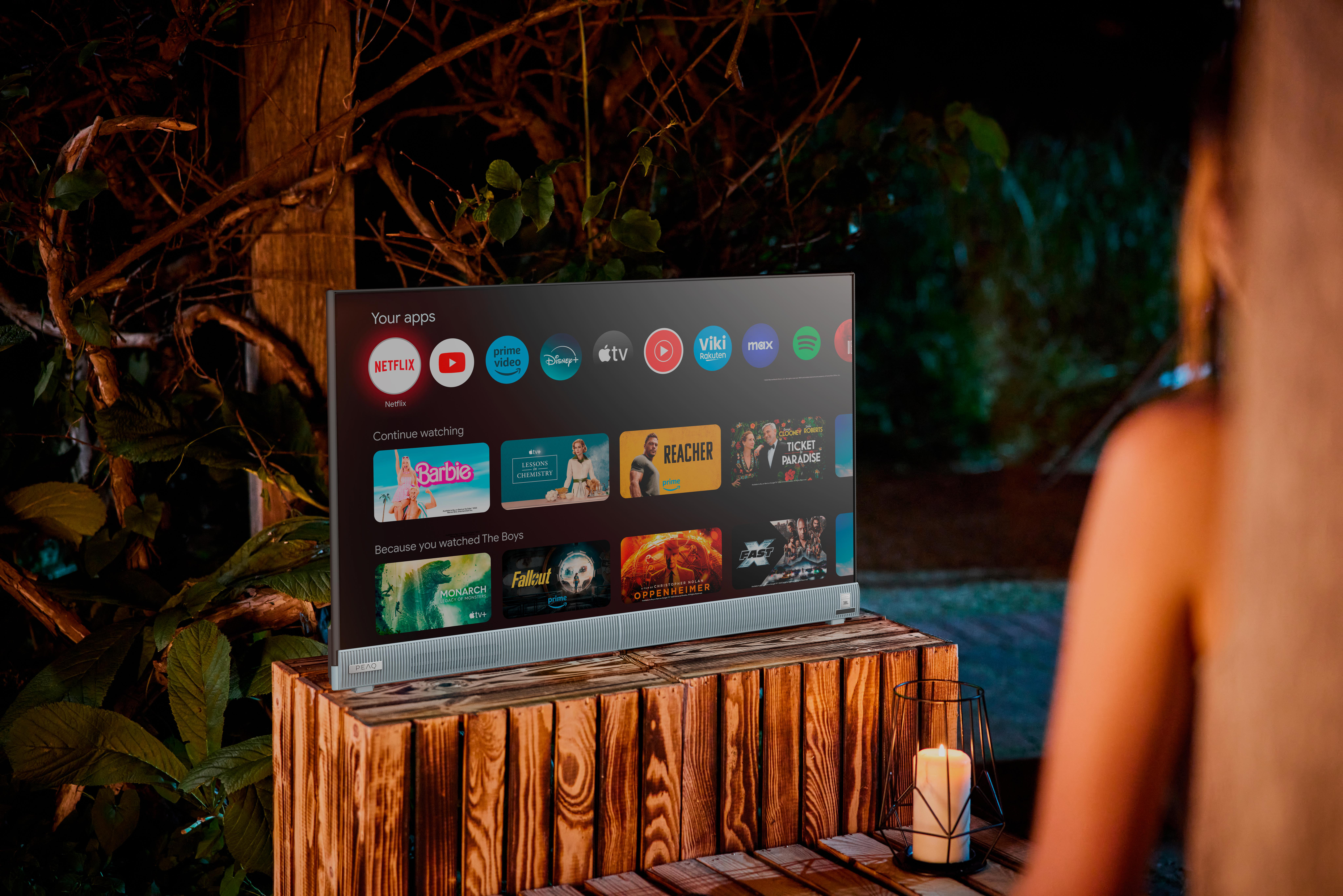 Fernseher auf Holzständer im Freien, mit App-Oberfläche auf dem Bildschirm.
