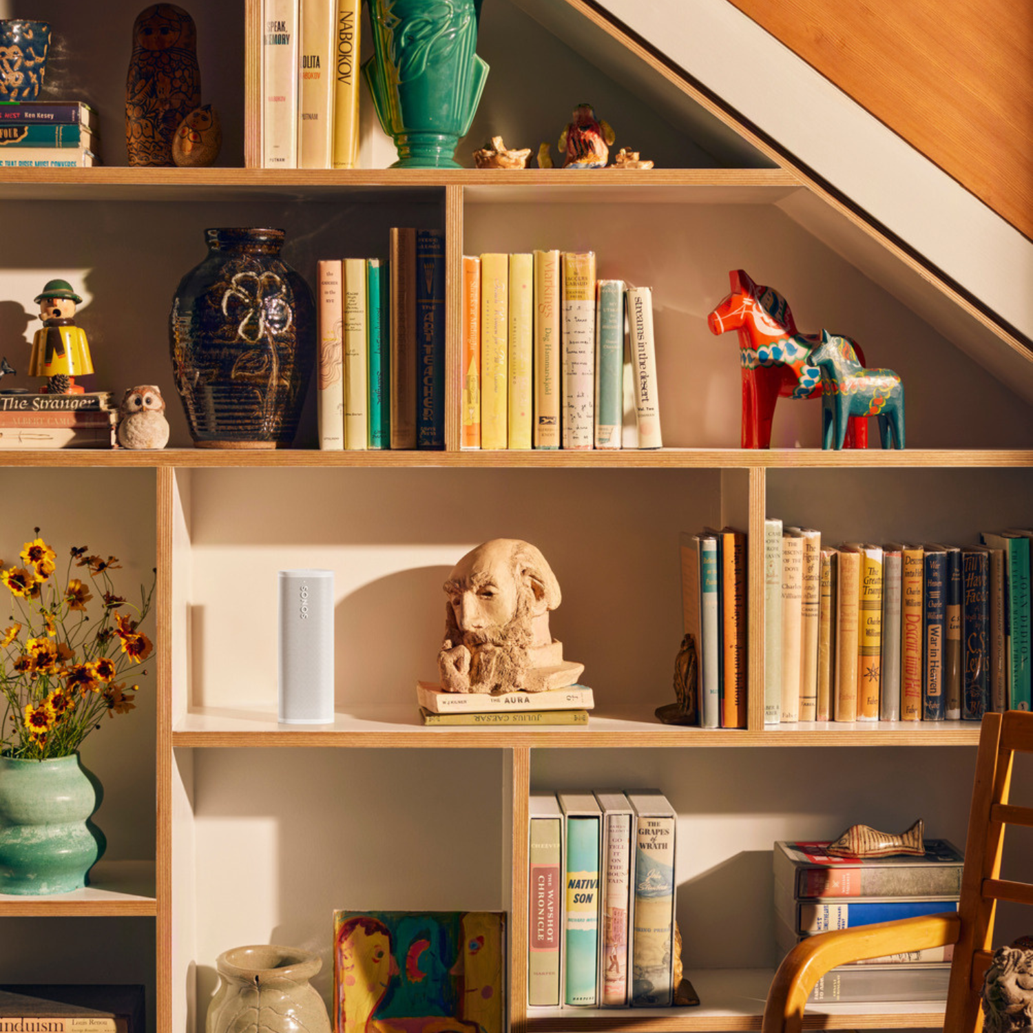 Estantería con libros, objetos de decoración y un altavoz.