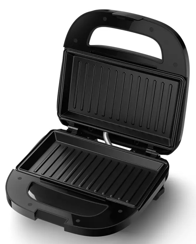 Otwarta czarna opiekacz do kanapek z żebrowaną powierzchnią do gotowania.