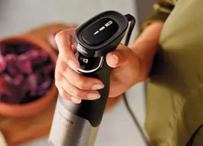 Ręka osoby trzyma czarny i srebrny blender.