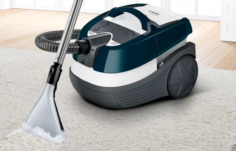 Odkurzacz czyszczący biały dywan, zbliżenie.