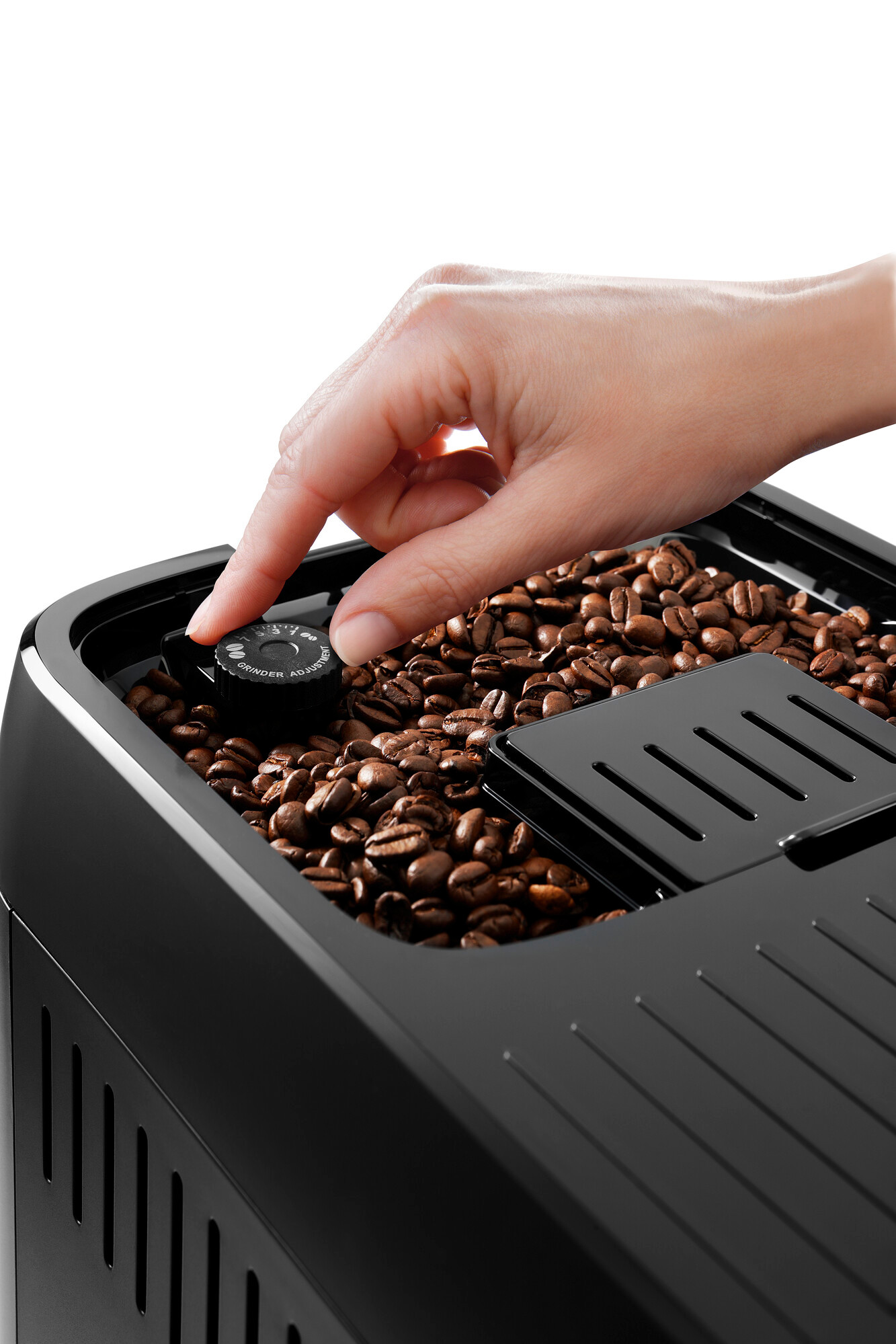 Bir kişinin eli, kavrulmuş fasulyelerle taşan bir kahve çekirdeği kabındaki bir kadranı ayarlıyor.