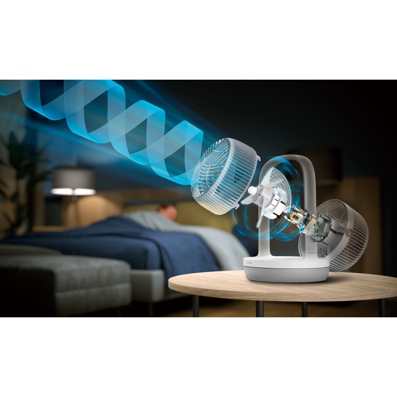 White and grey fan. Blue air flow illustration. Person in bed in the background.