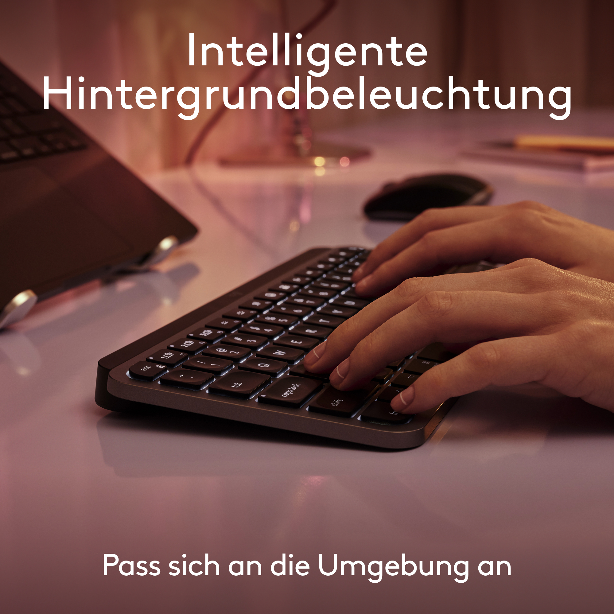 Hände tippen auf einer Tastatur mit beleuchteten Tasten, weicher rosa Hintergrund.