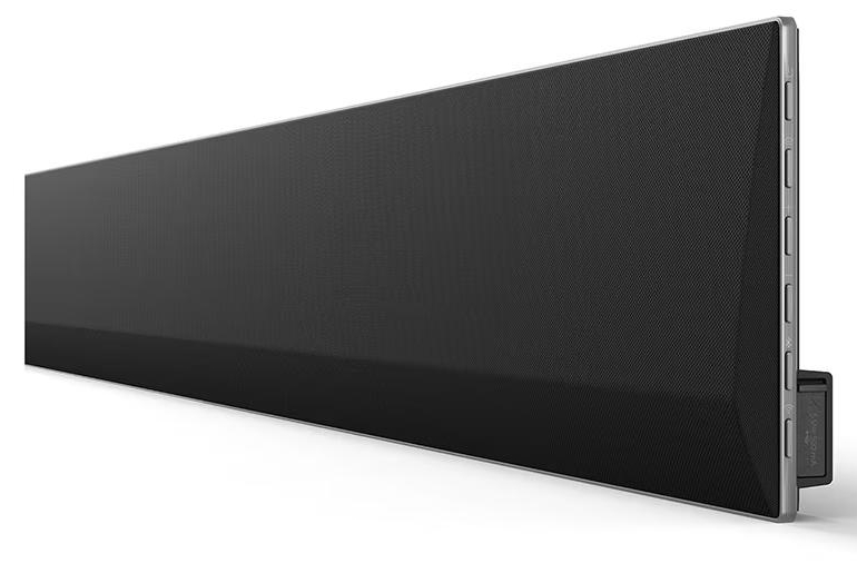 Długi, czarny soundbar z siatkowym przodem, zamontowany na białej ścianie.