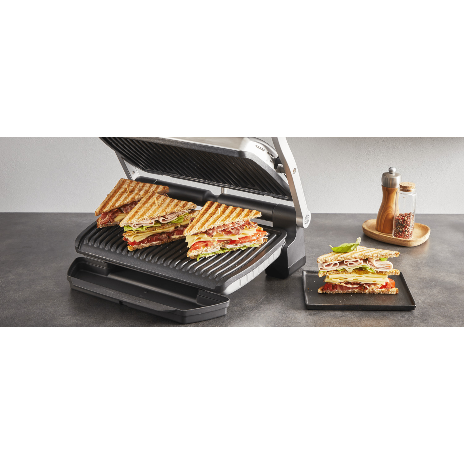 Sandwiches on a panini press, with additional sandwiches on a plate.