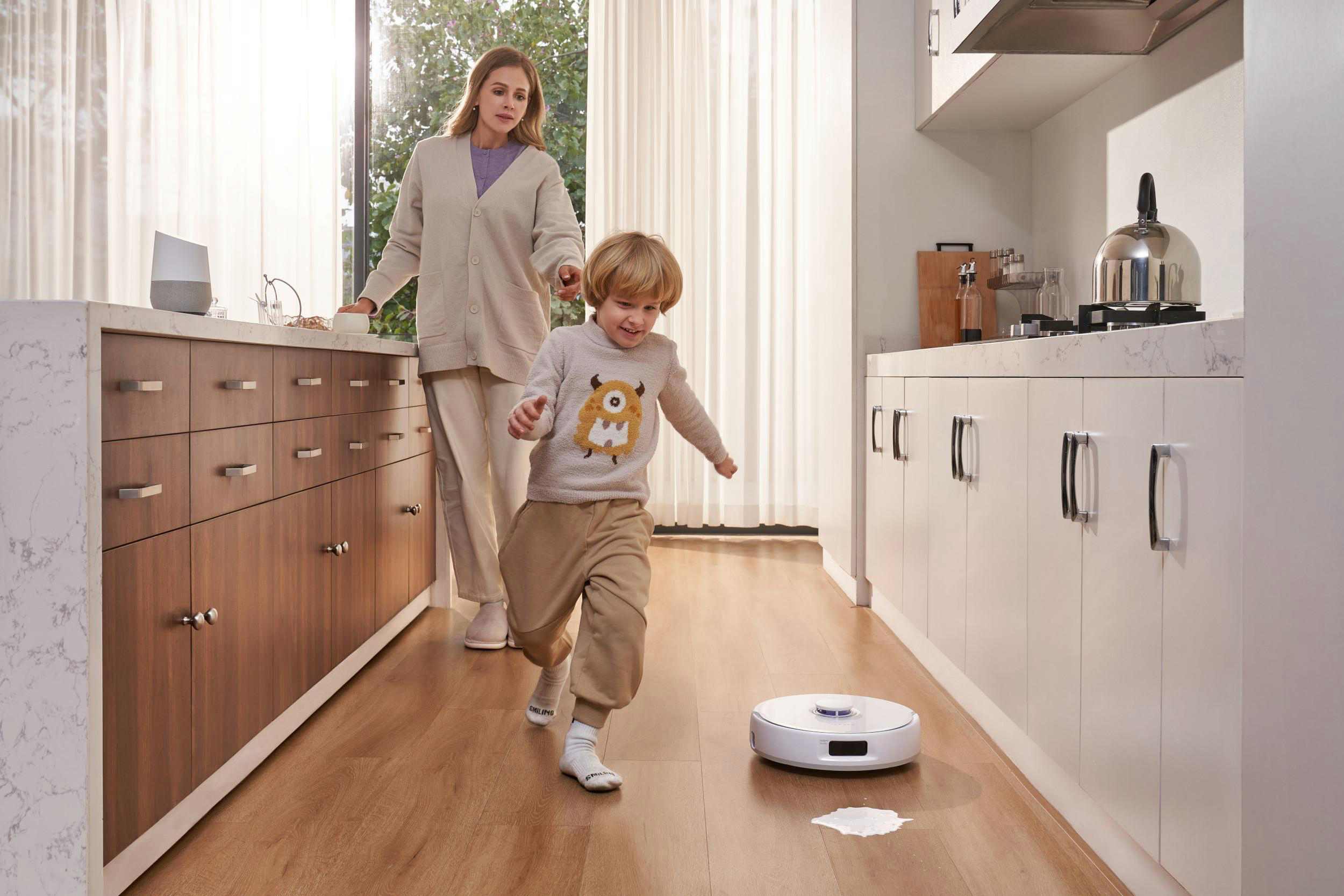 Kind rennt vor einem Roboter-Staubsauger in einer Küche weg.