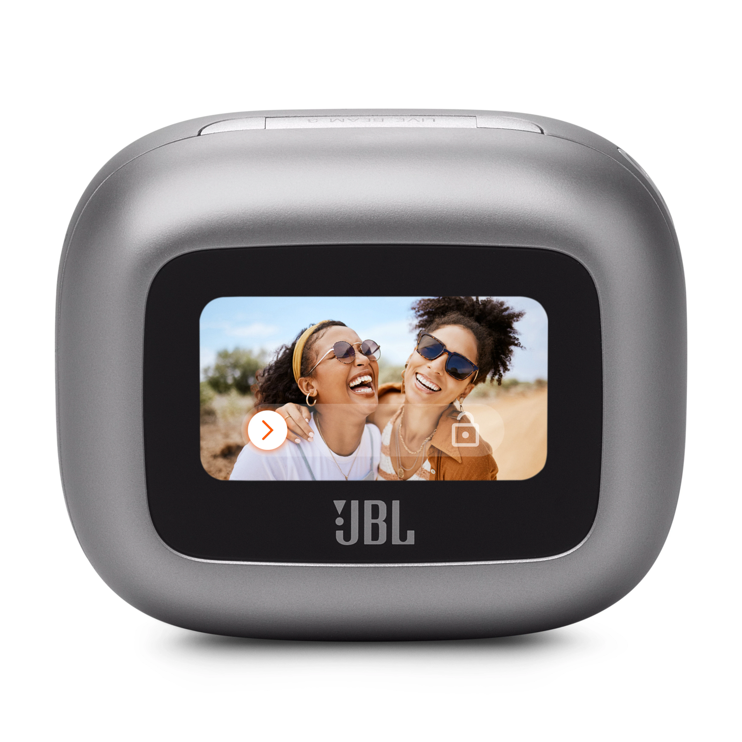 Zilveren JBL-luidspreker met een scherm waarop twee lachende vrouwen te zien zijn. De achtergrond is een woestijnlandschap.