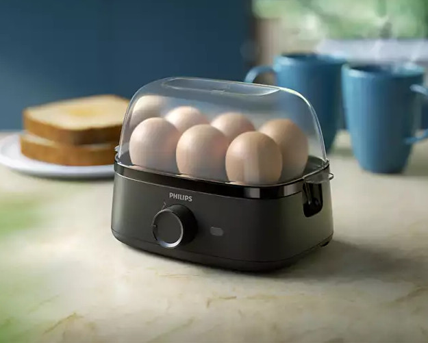 Czarny garnek do gotowania jajek Philips z jajkami w środku, na stole.