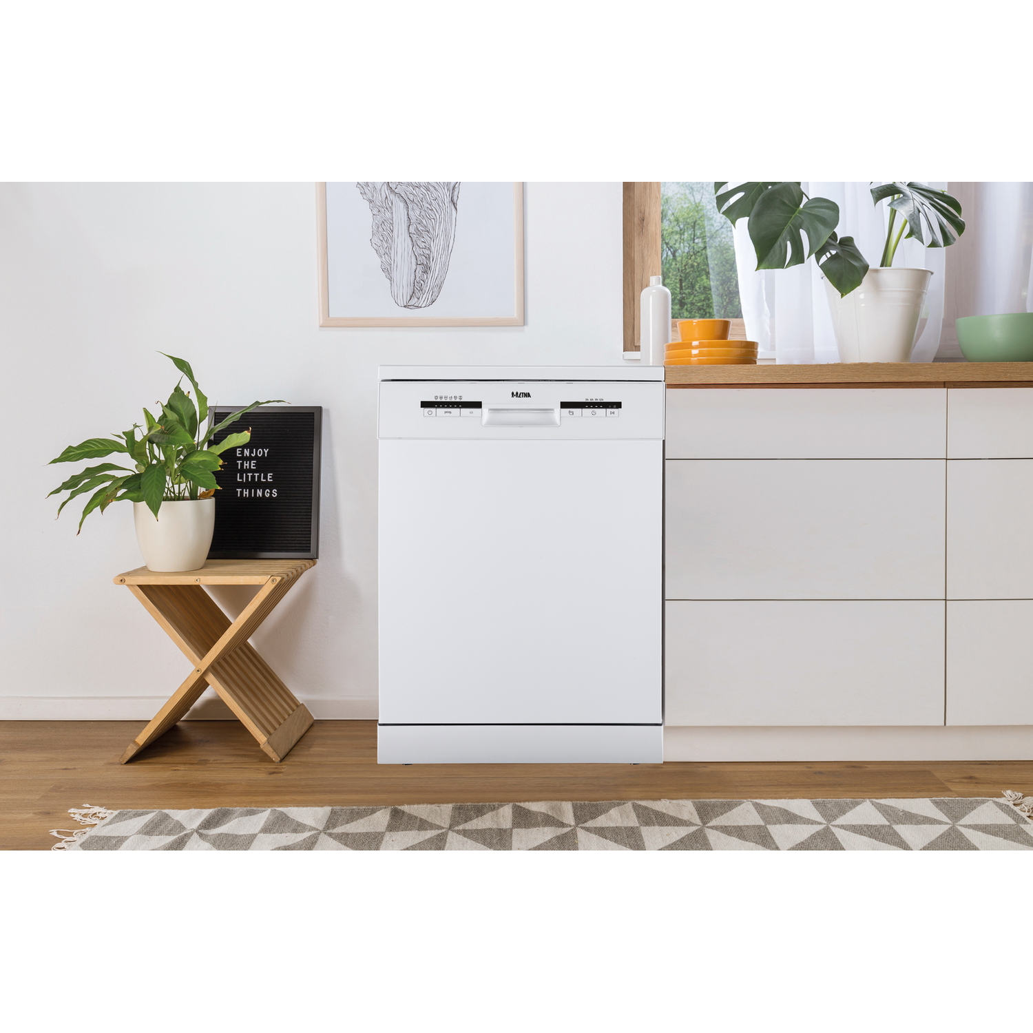 Een witte vaatwasser in een keuken. Een plant staat op een krukje. Een raam en andere keukenelementen zijn zichtbaar.