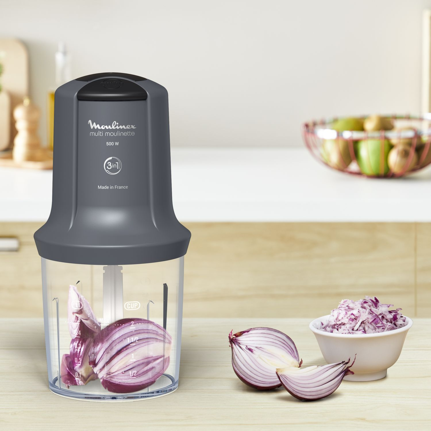 A food processor with onion inside and beside cut onions in a bowl. Kitchen setting.