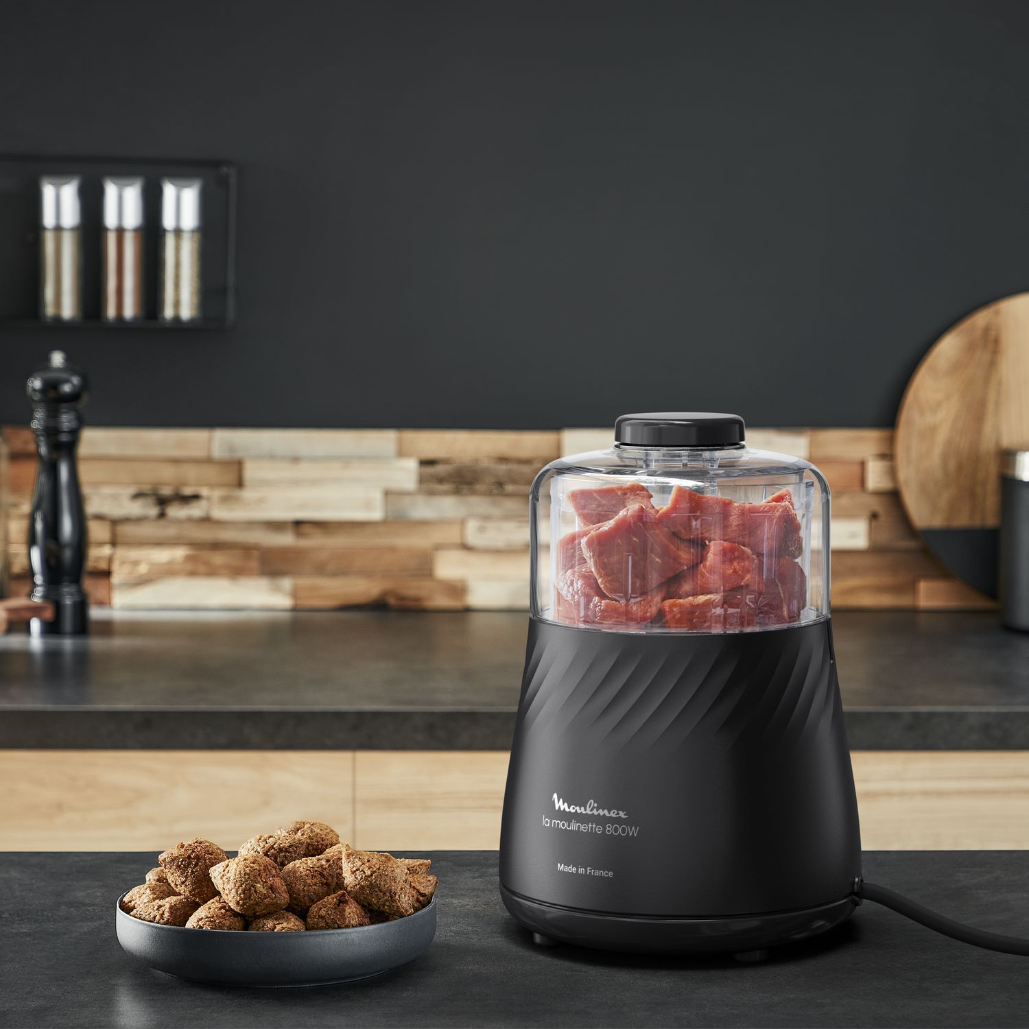 Black Moulinex food processor with a transparent container filled with meat.
