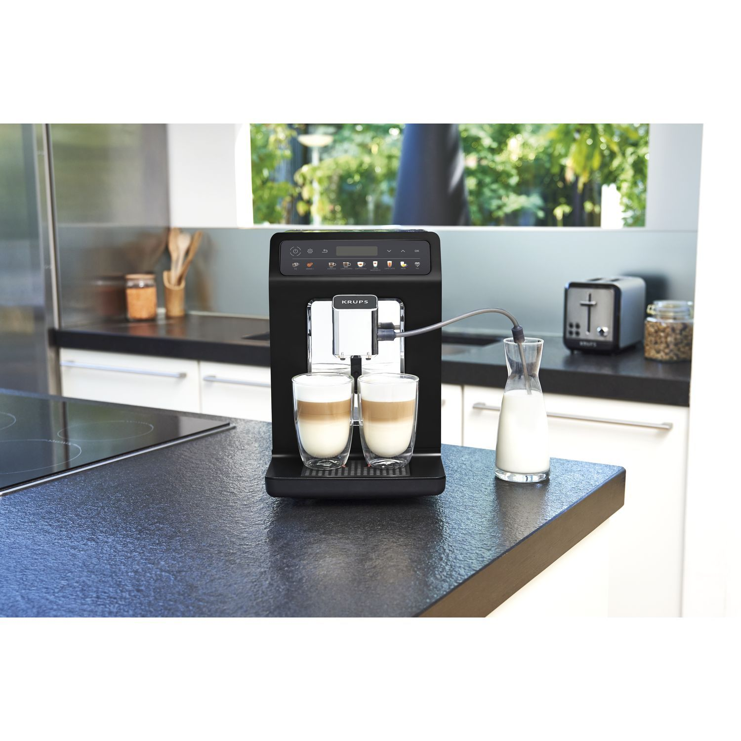 Black coffee machine with two cups of latte macchiato on the counter. 