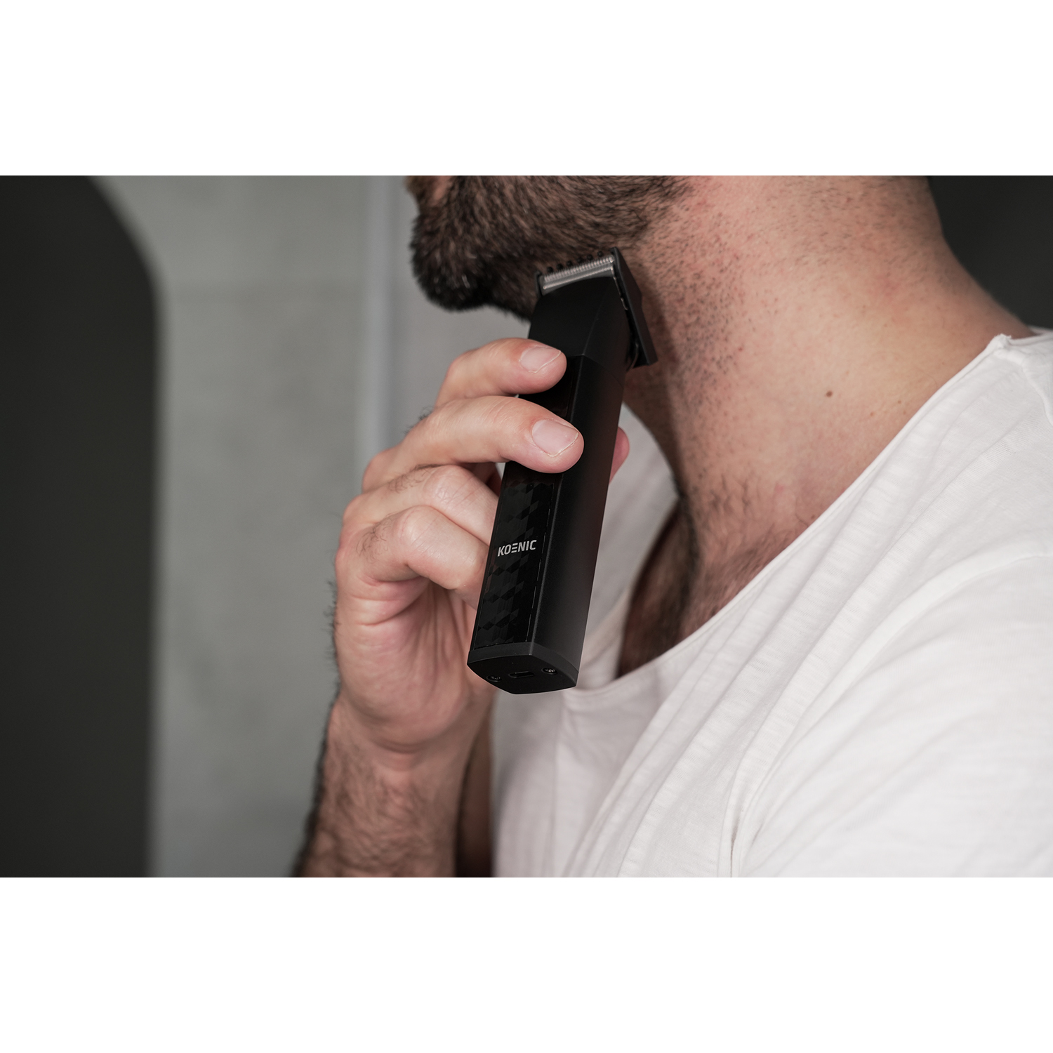 Un uomo si rade il collo con un regolabarba nero. Il regolabarba è tenuto in mano.
