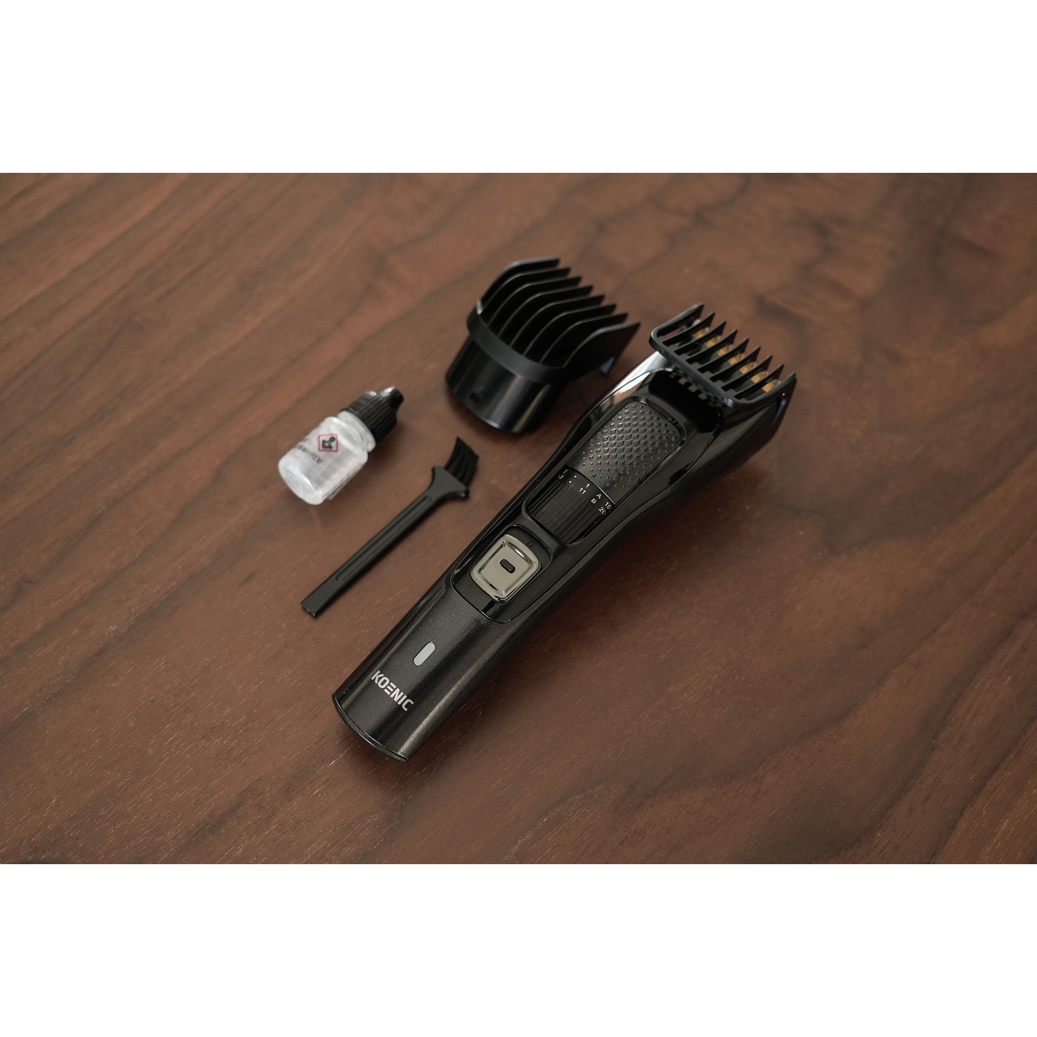 Regolabarba nero con accessori: flacone di olio, spazzola e accessorio, su superficie in legno.
