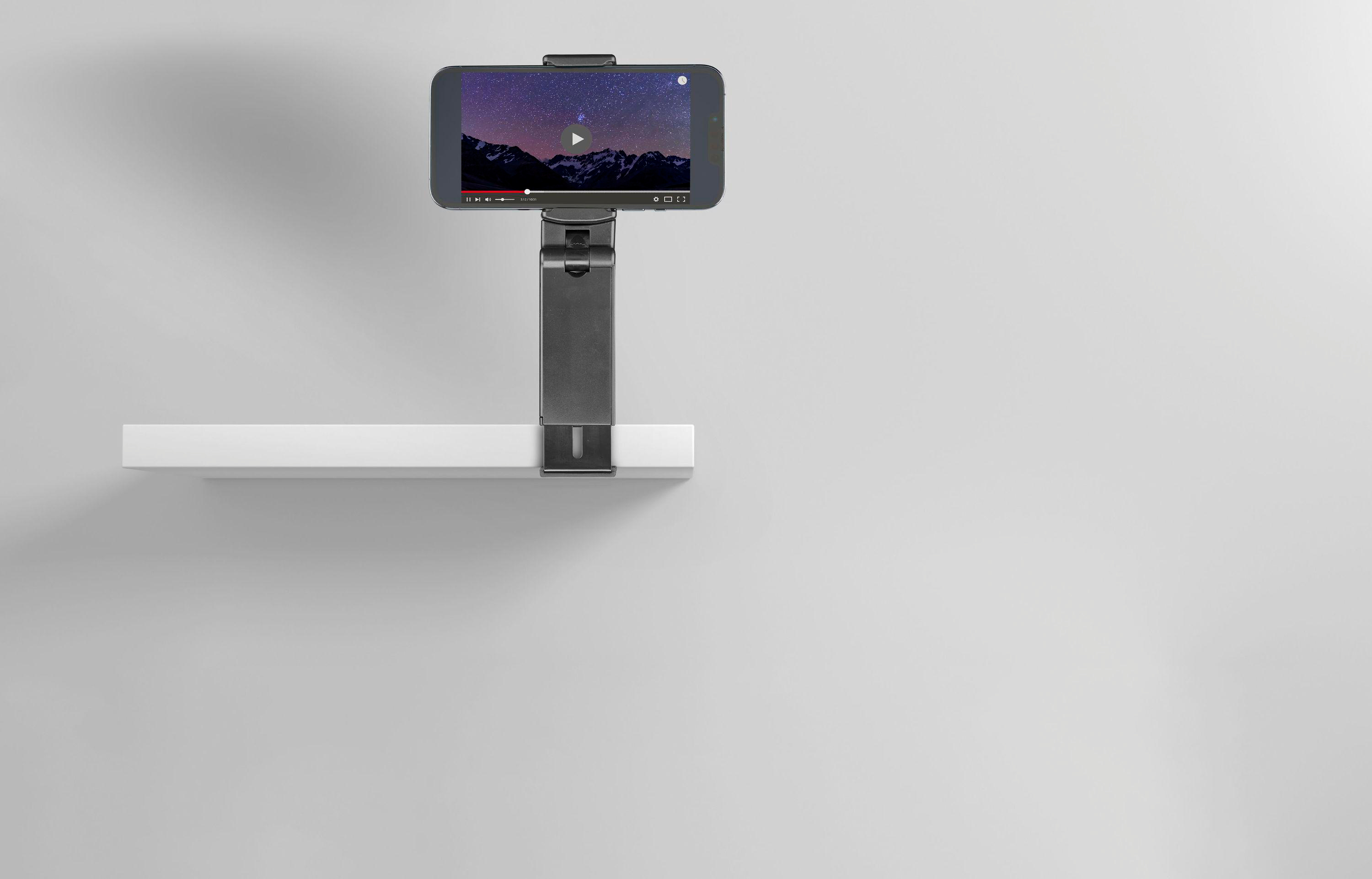 Ein Smartphone auf einem Ständer zeigt ein Video eines Sternenhimmels auf einem weißen Regal.