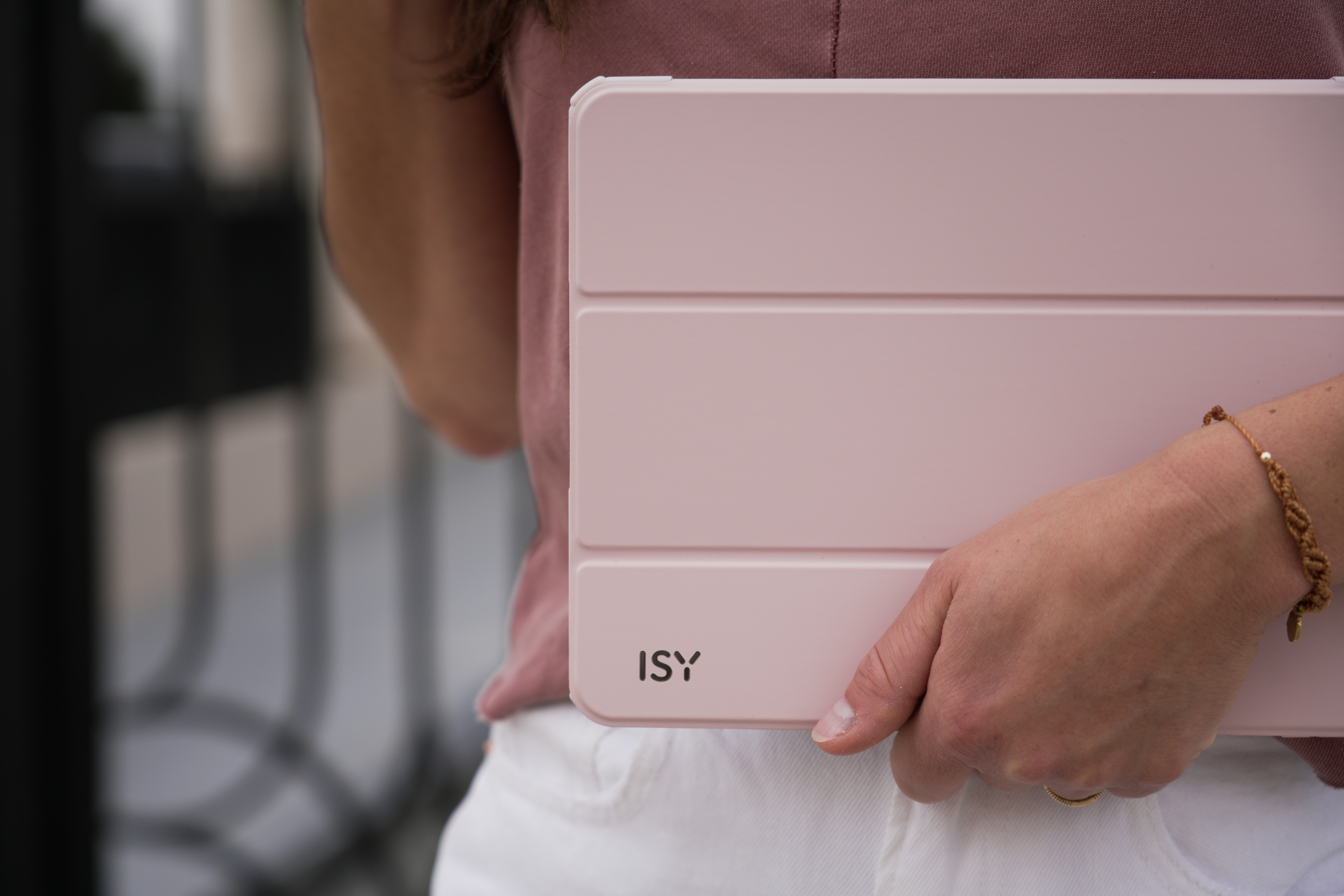 Person hält eine pinke Tablet-Hülle. Auf der Hülle steht 'ISY'.