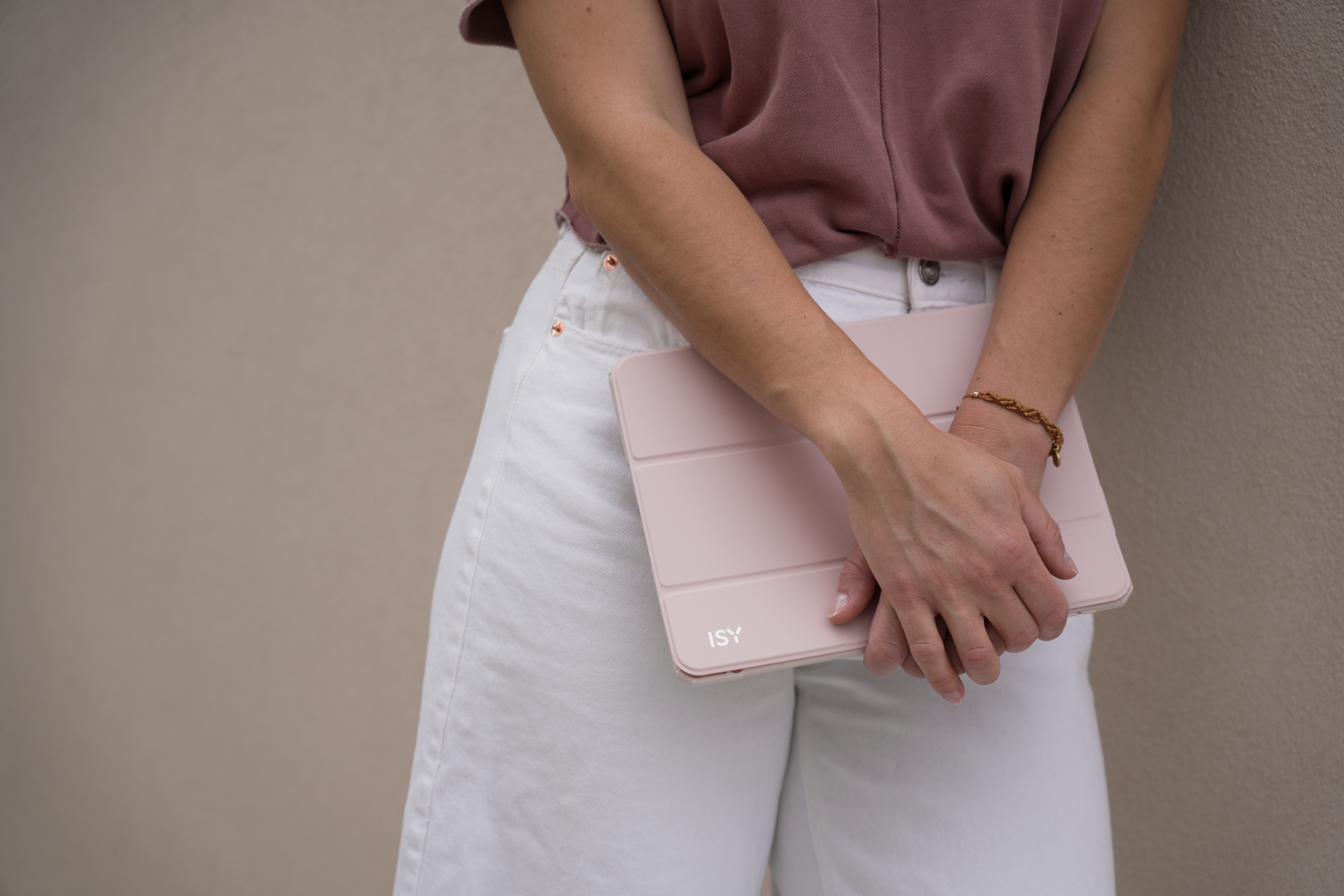 Eine Frau hält ein pinkfarbenes Tablet in einer pinkfarbenen Hülle. Sie trägt ein pinkfarbenes Hemd und weiße Hose.