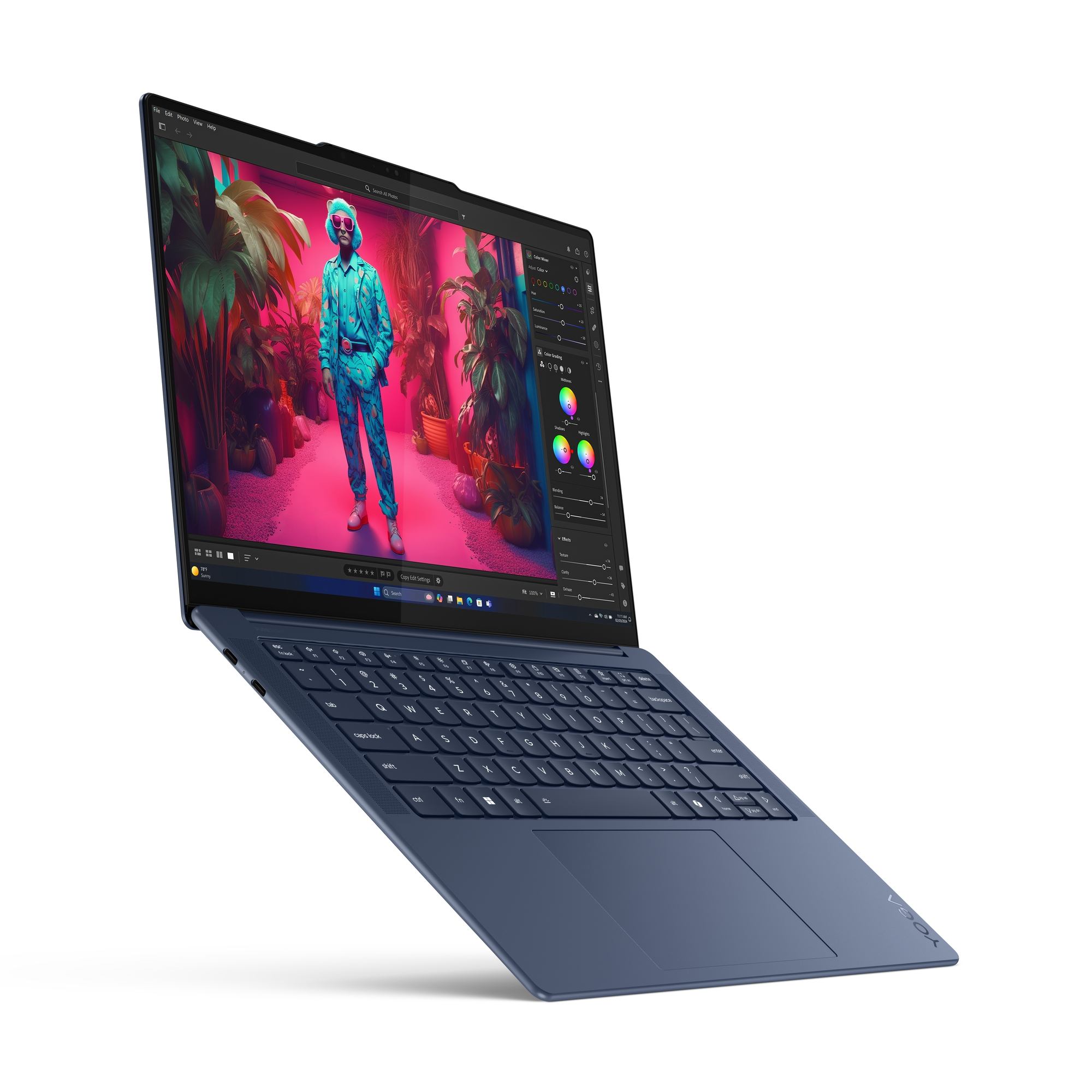 Niebieski laptop otwarty, pokazujący kolorowy ekran z osobą w okularach przeciwsłonecznych i kolorowymi roślinami w tle.