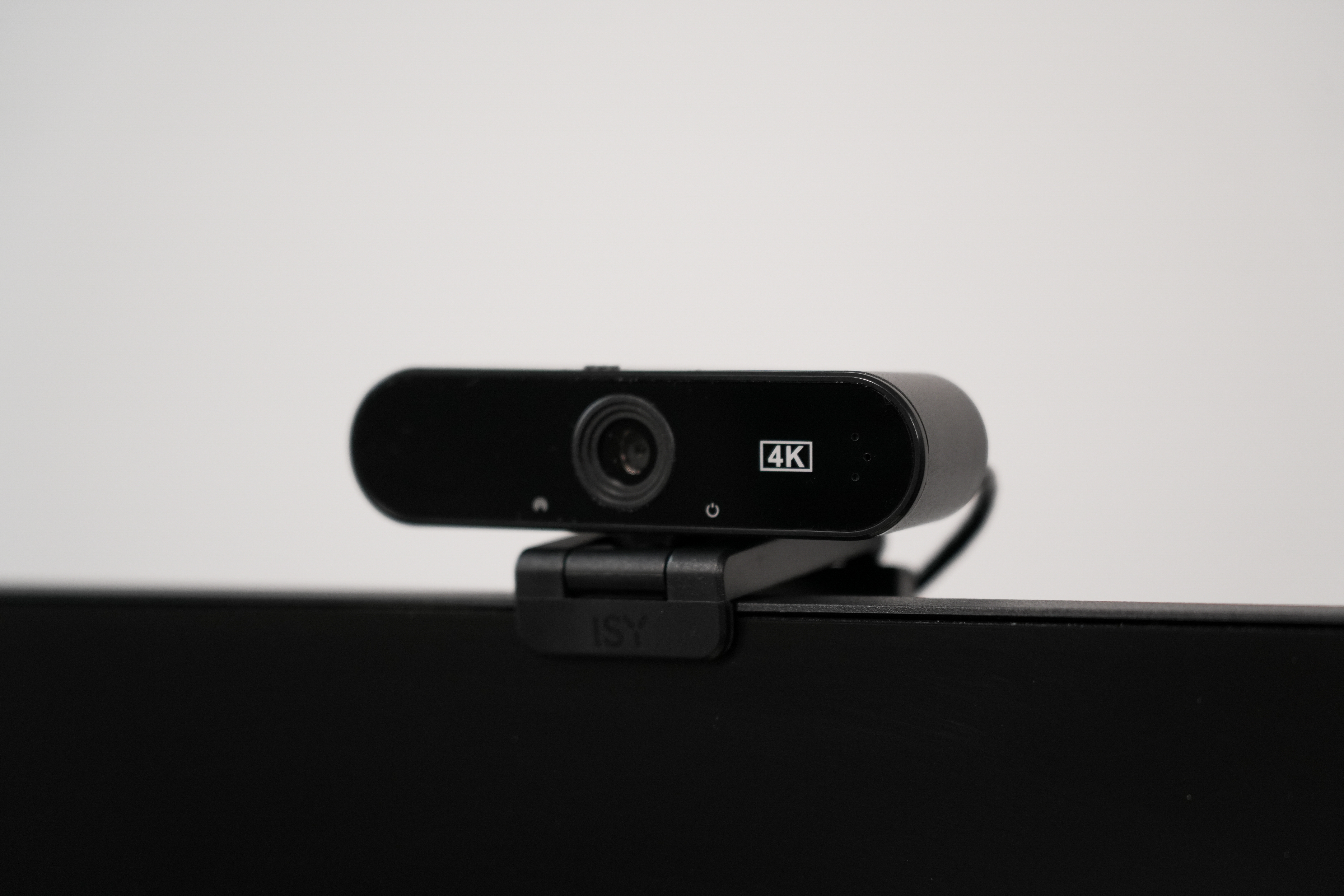 Eine schwarze Webcam mit einem 4K-Logo sitzt auf einem schwarzen Monitor. Der Hintergrund ist weiß.