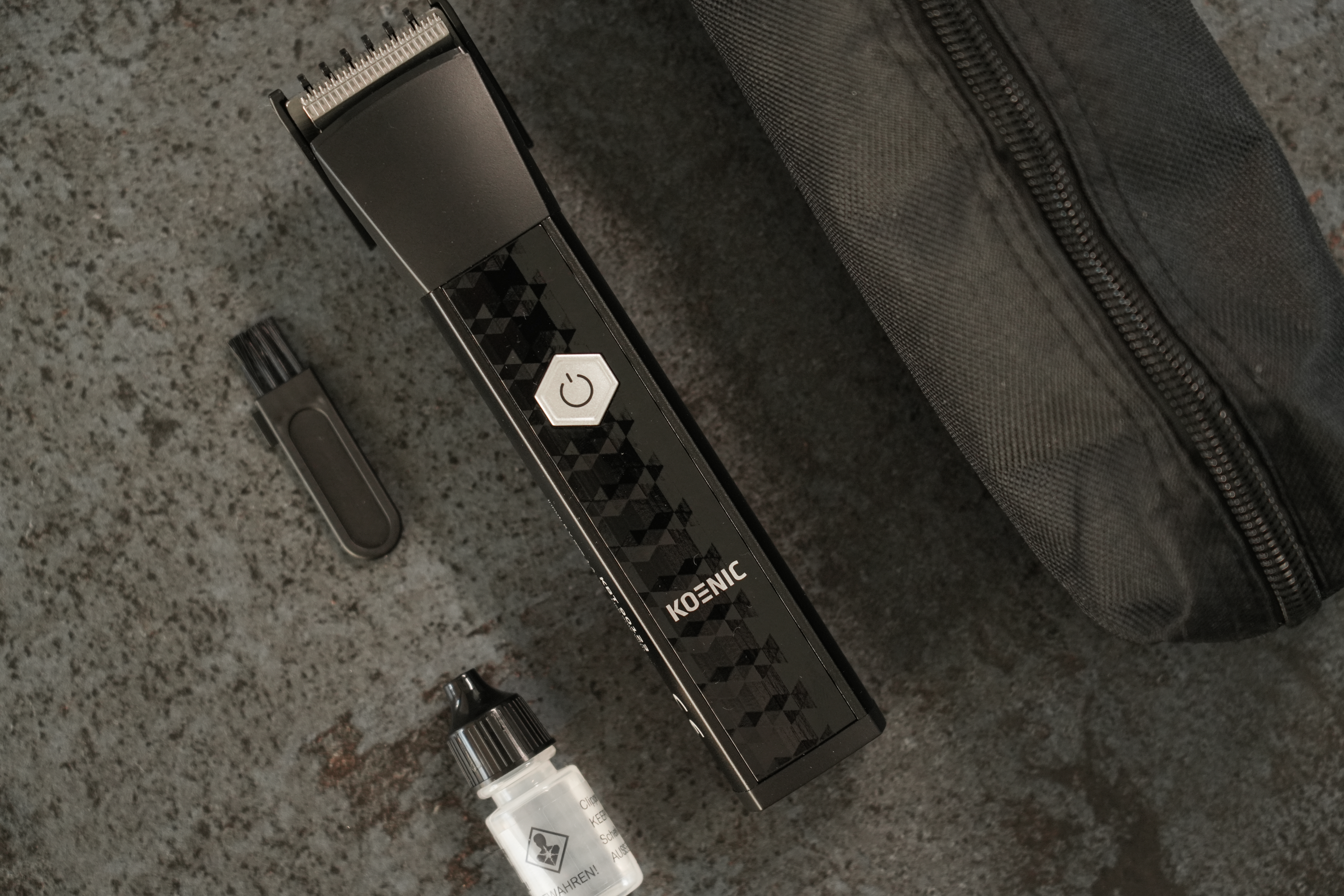 Schwarzer Haarschneider mit Zubehör: kleiner Bürste, Ölflasche und schwarzer Tasche.