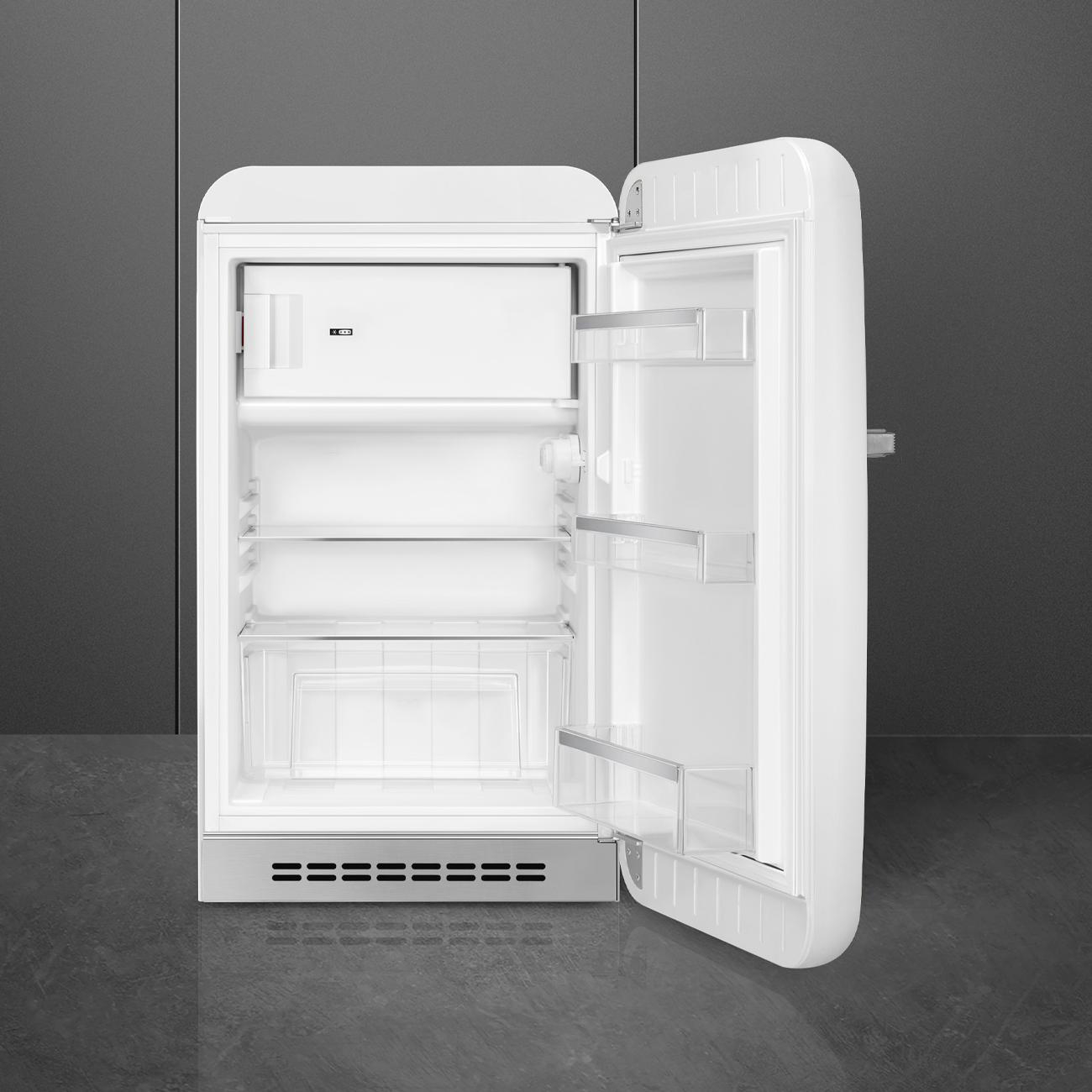 Ein weißer Kühlschrank im Retro-Stil, geöffnet, zeigt Regale und Gefrierfach.