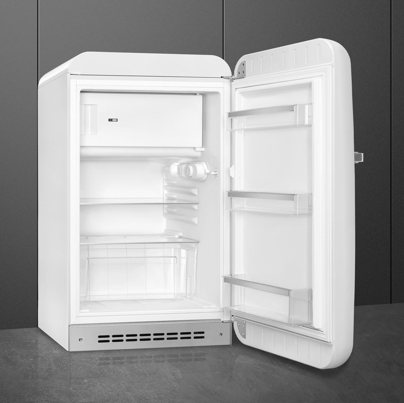 Weißer Kühlschrank im Retro-Stil, offene Tür. Innenraum mit Regalen und Gefrierfach.