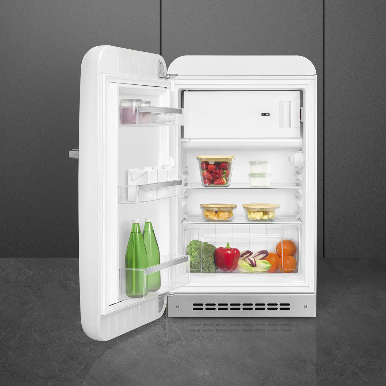 Ein weißer Kühlschrank mit offener Tür, der Regale mit Lebensmitteln wie Obst und Gemüse zeigt.