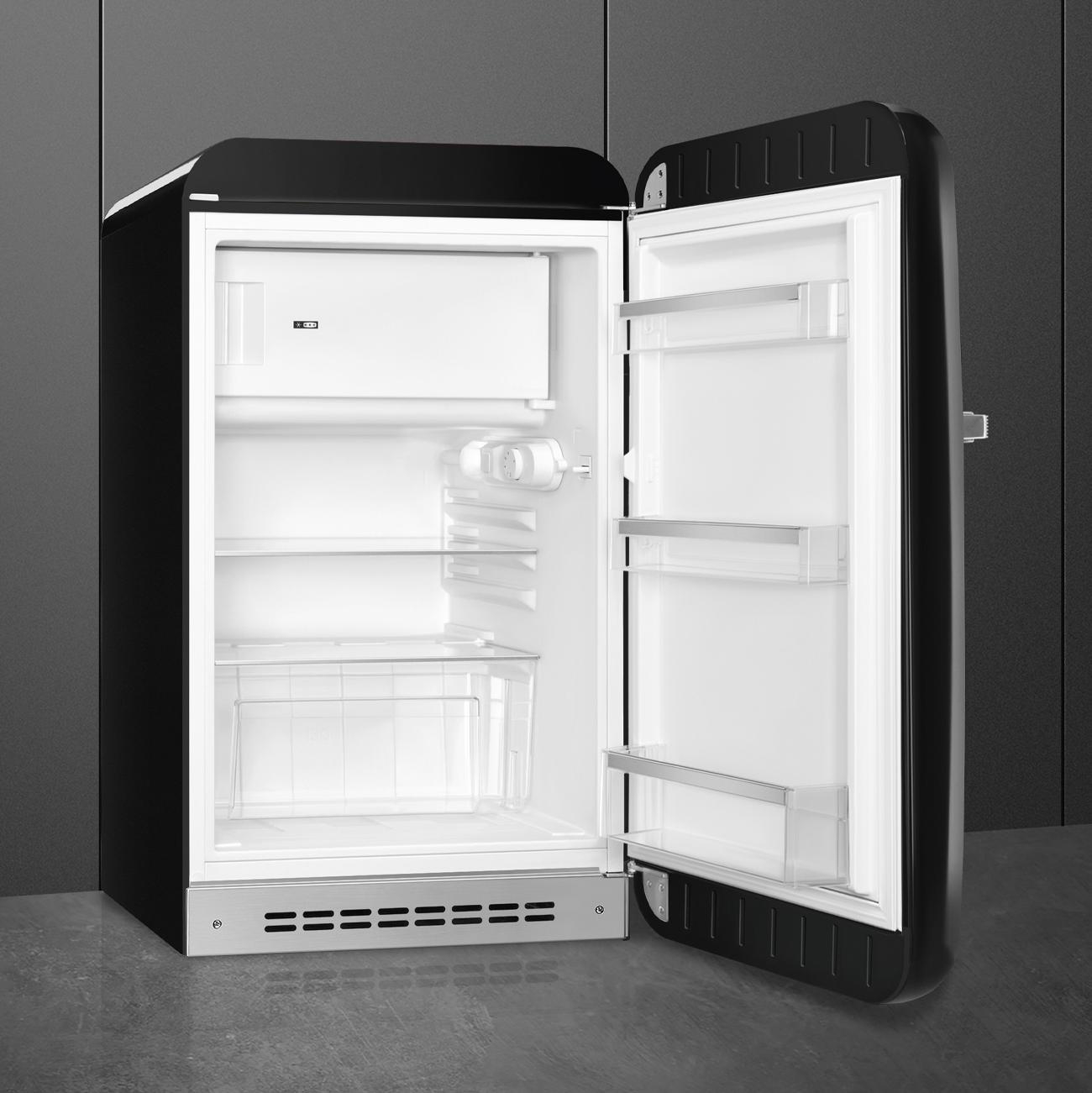 Ein schwarzer und weißer Mini-Kühlschrank mit offener Tür, zeigt Regale und Inhalt.