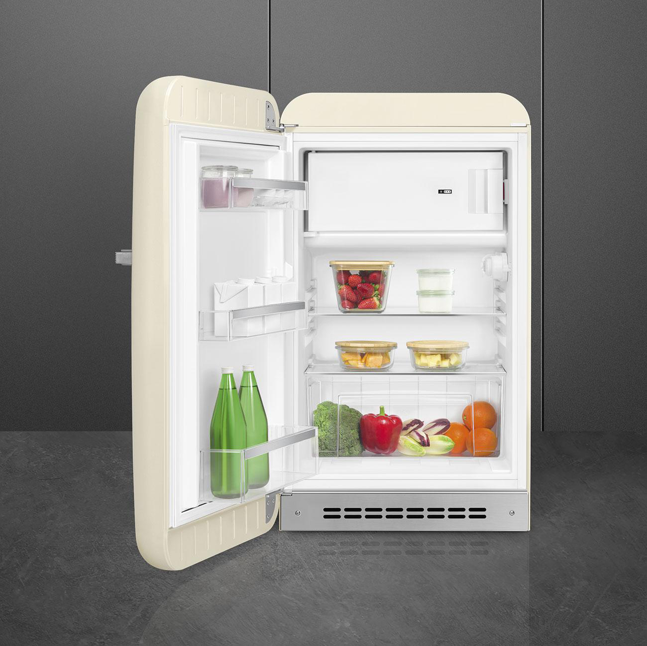 Offener cremefarbener Retro-Kühlschrank, der Lebensmittel zeigt. Grüne Flaschen an der Tür.