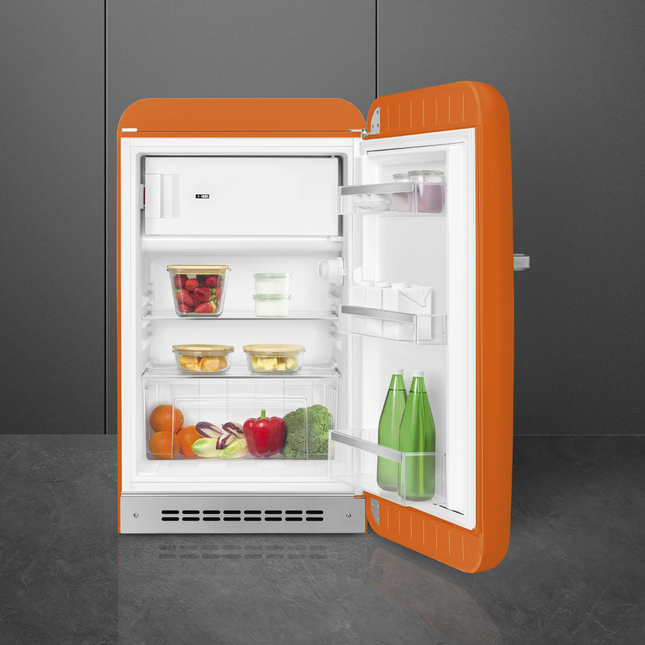 Oranger Retro-Kühlschrank mit offener Tür, zeigt Obst, Gemüse und Flaschen im Inneren.