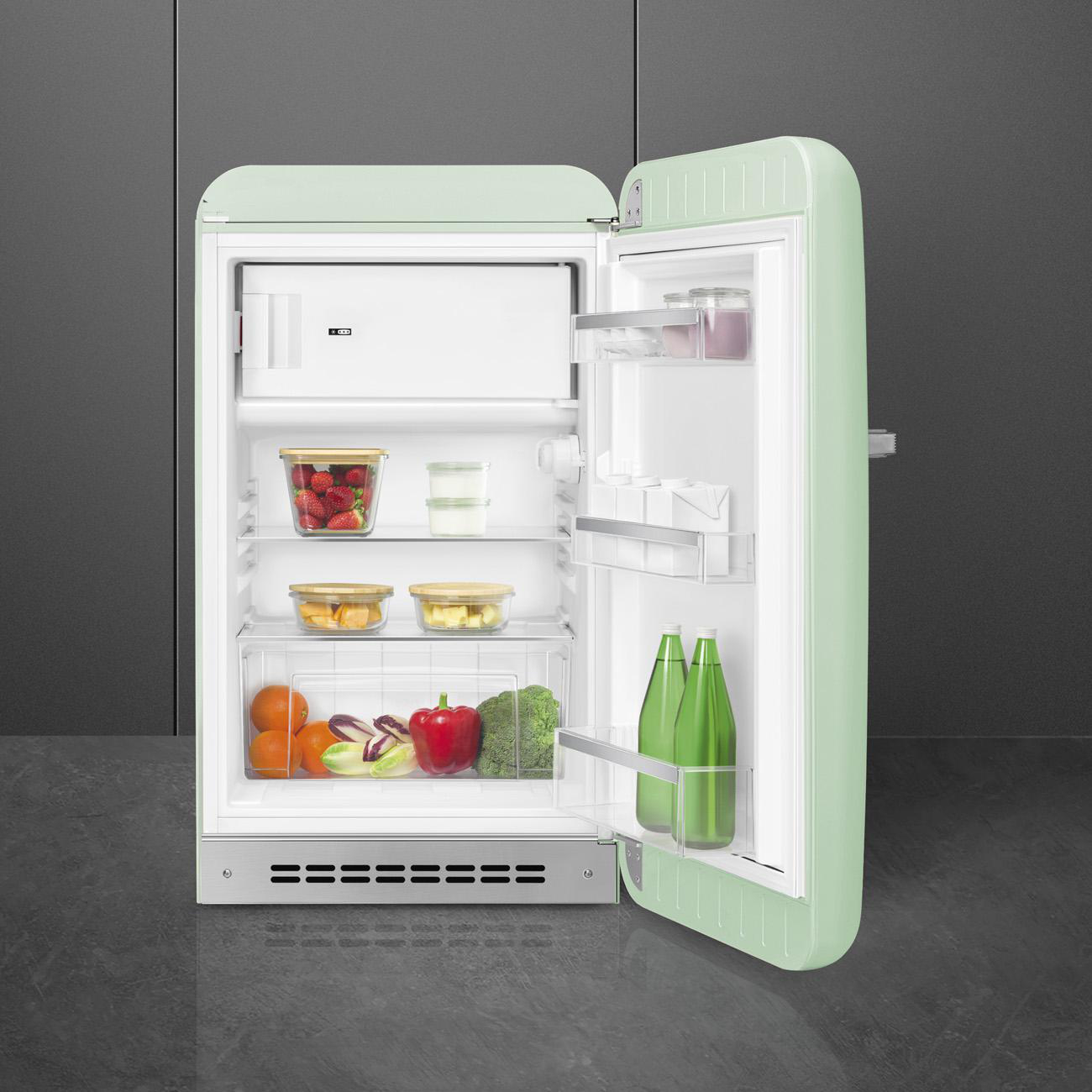 Minzgrüner Smeg Kühlschrank mit offener Tür, gefüllt mit Lebensmitteln und Regalen.