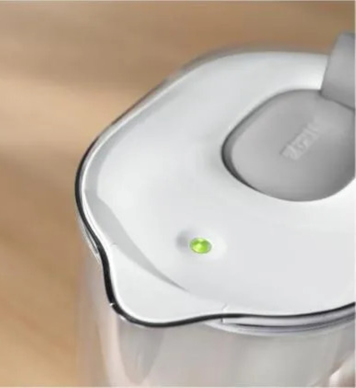 Zbliżenie białego dzbanka z filtrem do wody z zielonym światłem na pokrywie.