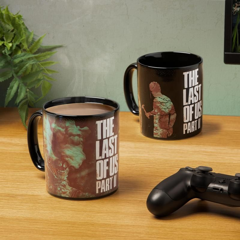 Két bögre The Last of Us dizájnnal és egy játékvezérlővel.