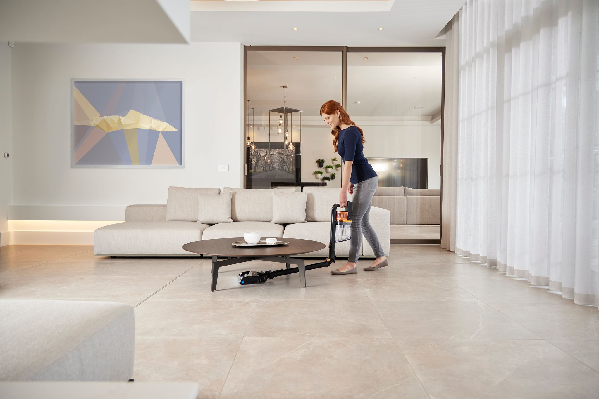 Une femme passe l'aspirateur dans un salon moderne.