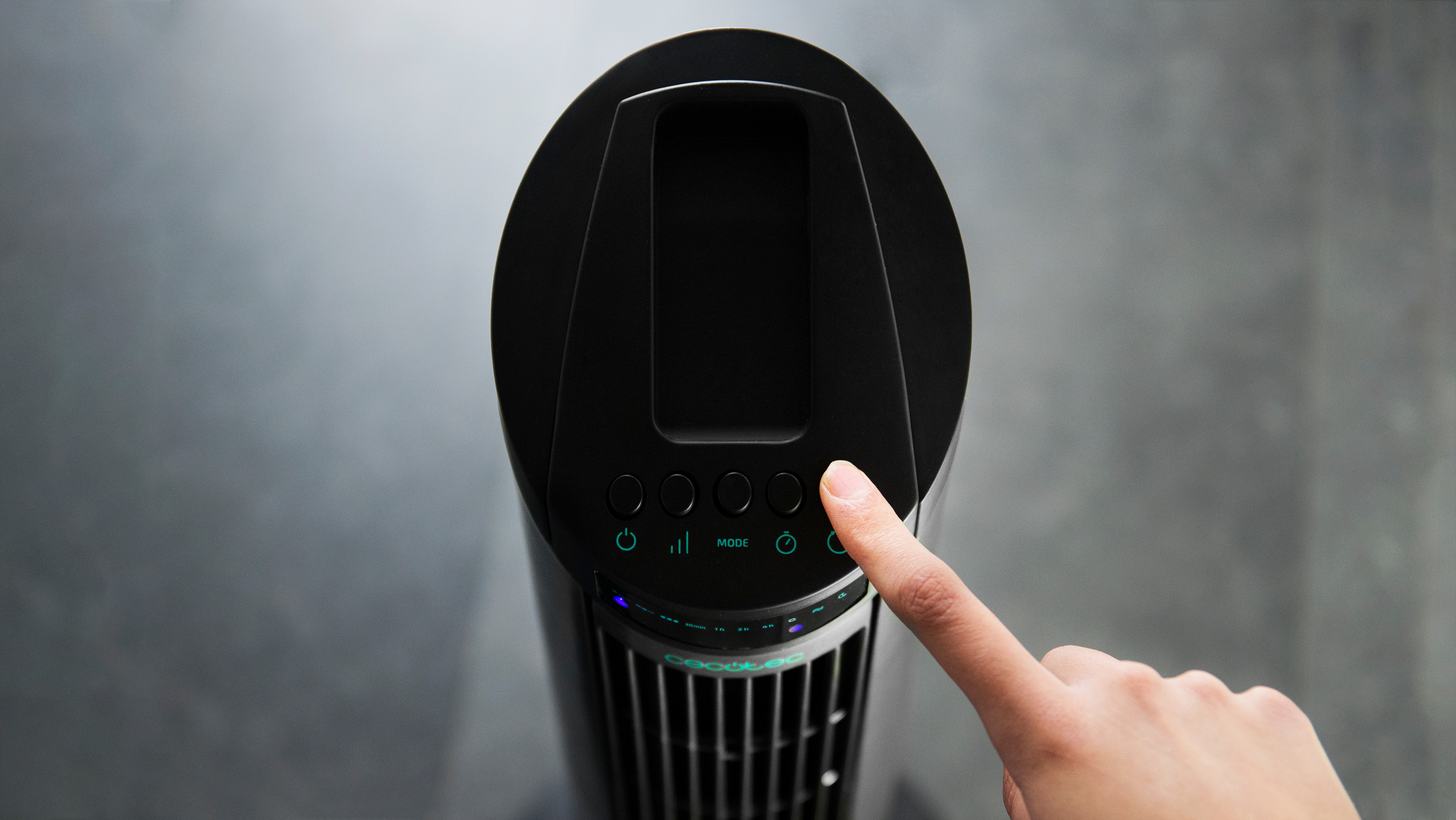 Un dedo presionando un botón en un ventilador negro. El ventilador tiene una pantalla digital.