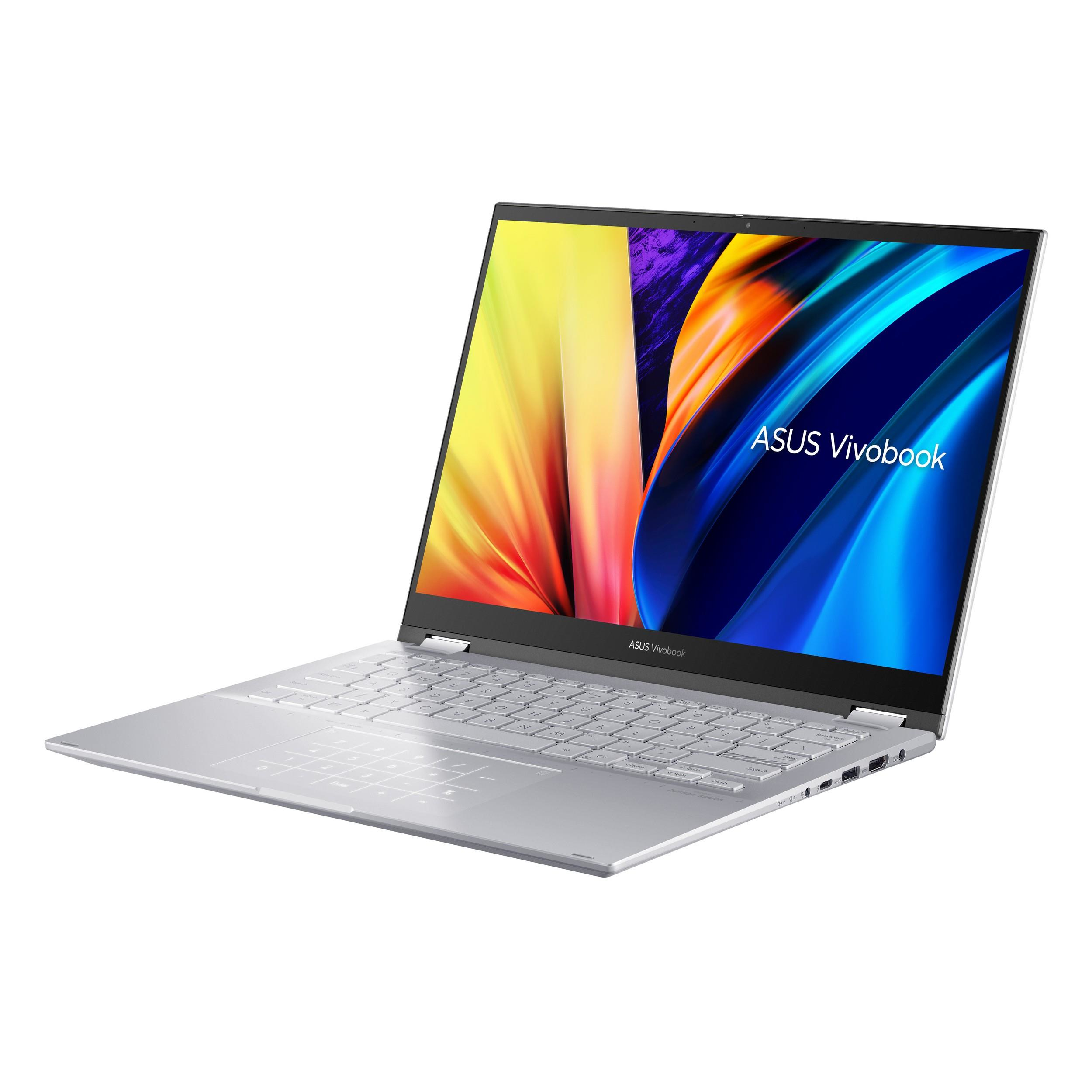 Una computadora portátil plateada está abierta, mostrando una pantalla colorida. La computadora portátil está sobre una superficie blanca.