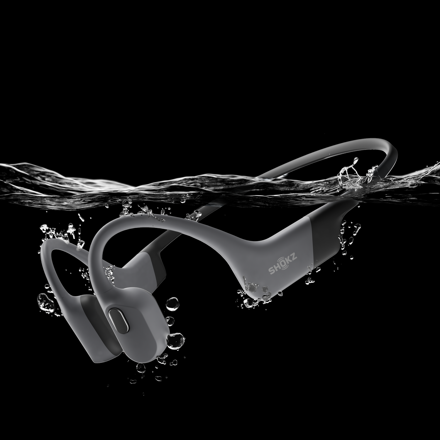 Gray bone-conduction headphones are submerged in water, with bubbles and ripples.