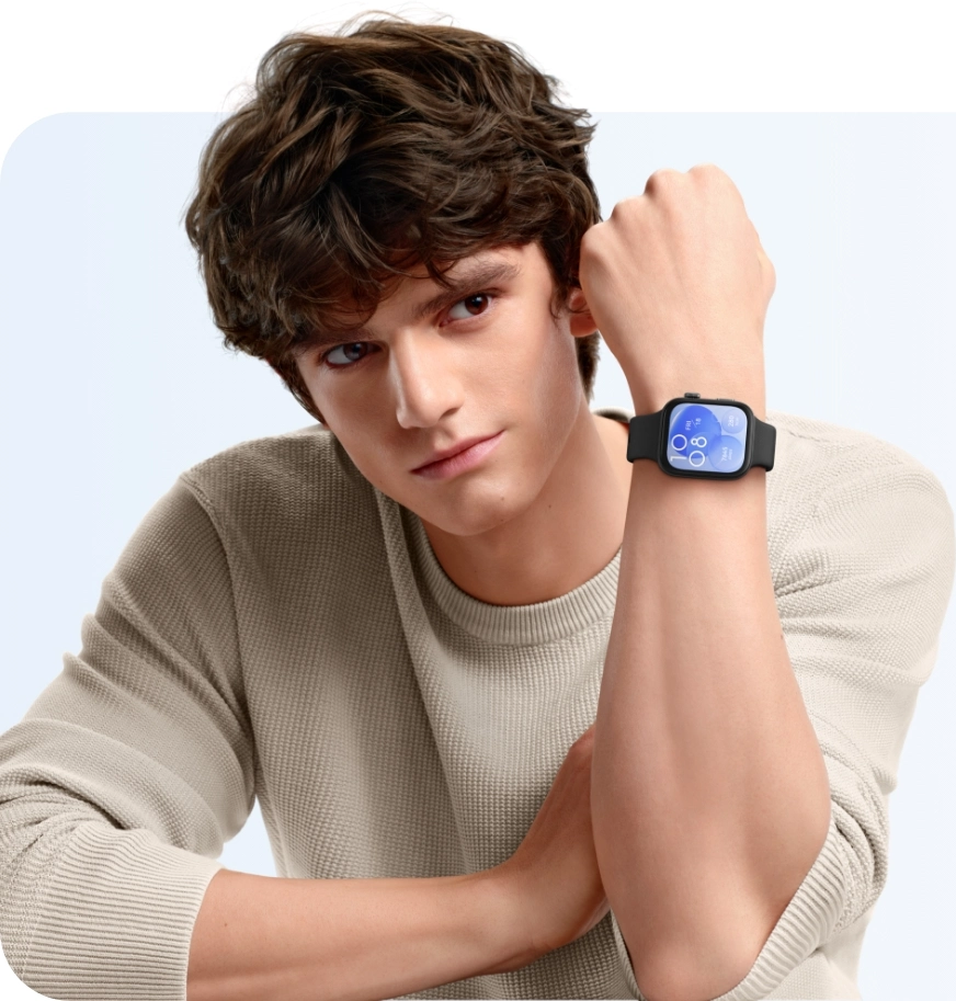 Homme portant une montre noire à écran bleu. Il porte un pull beige et a les cheveux bruns.