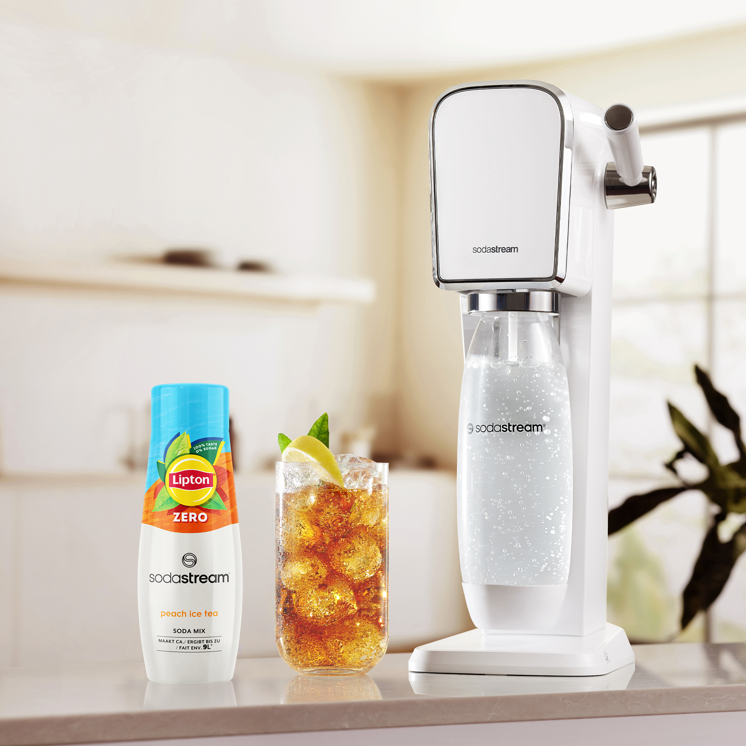 SodaStream machine with a glass of ice tea and a bottle of soda mix.
