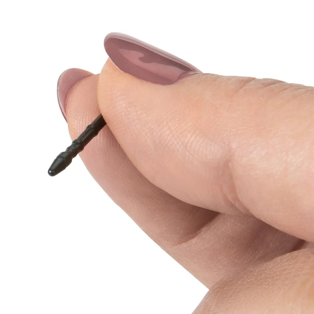 La mano de una persona sosteniendo un bolígrafo negro. La persona tiene esmalte de uñas rosa.
