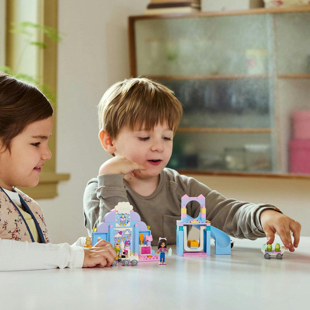 Zwei Kinder spielen mit einem Lego-Set. Das Set scheint ein kleines Gebäude mit Figuren zu sein.