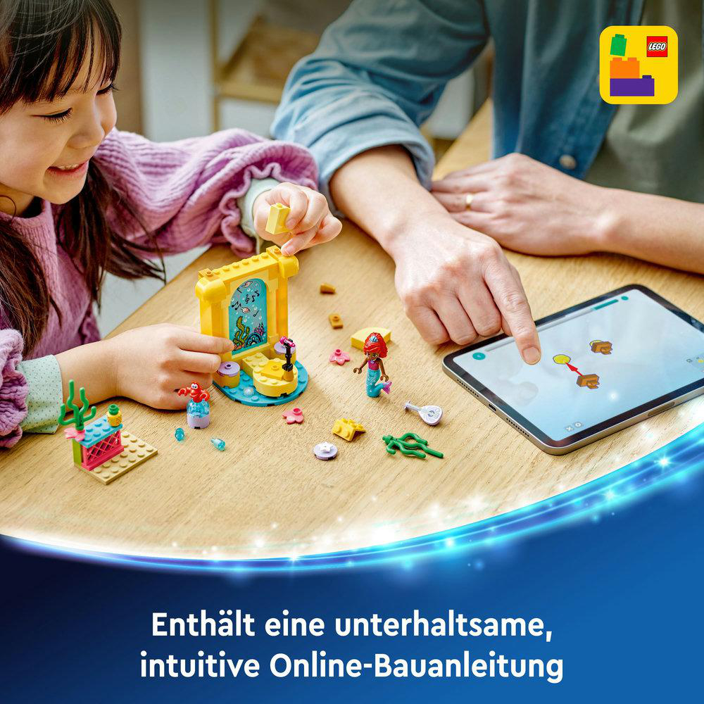 Mädchen und Erwachsener spielen mit Lego. Lego-Set mit Figuren auf einem Holztisch. Tablet wird benutzt.