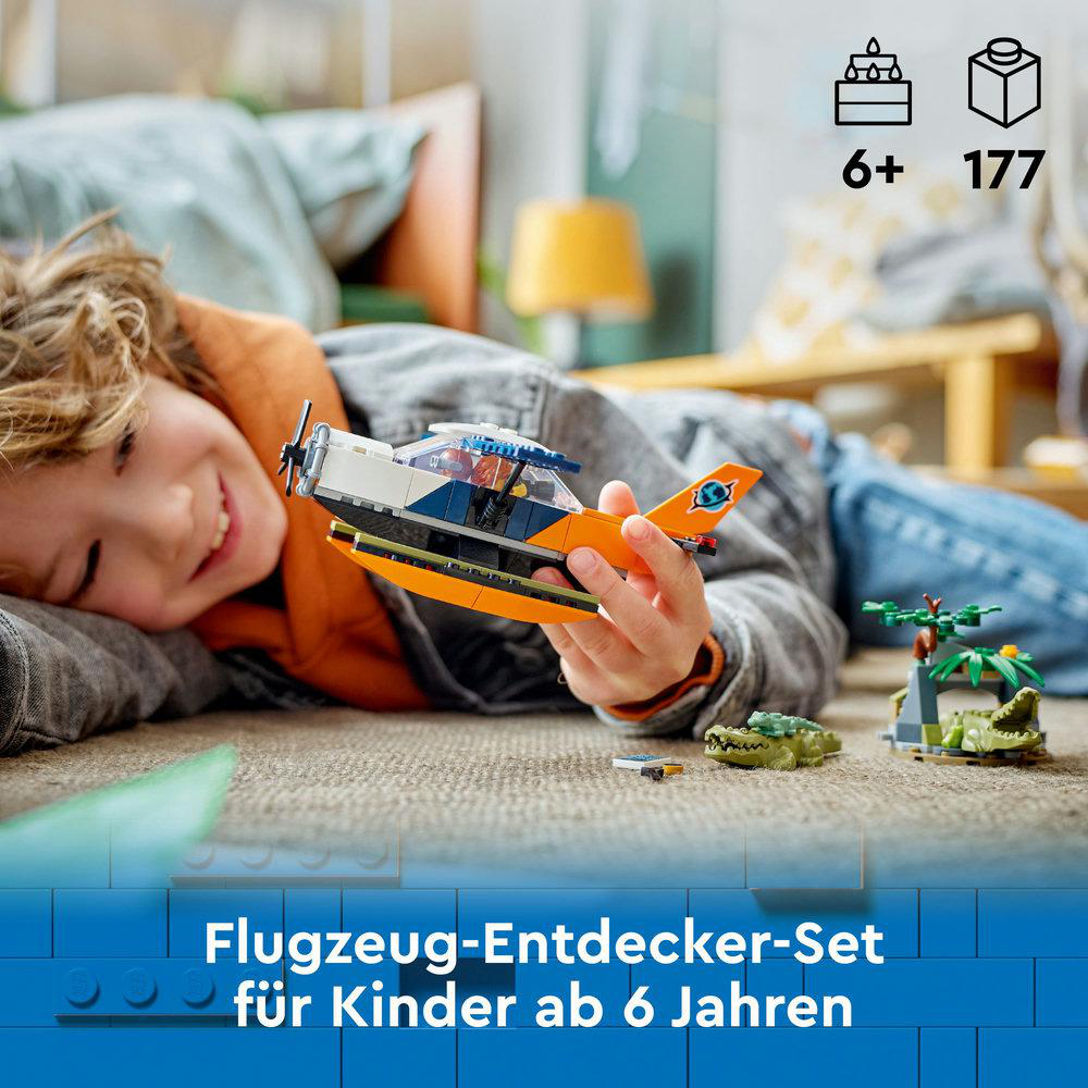Ein Junge spielt mit einem Lego-Flugzeugset, auf einem Tisch mit Krokodil-Spielzeug.