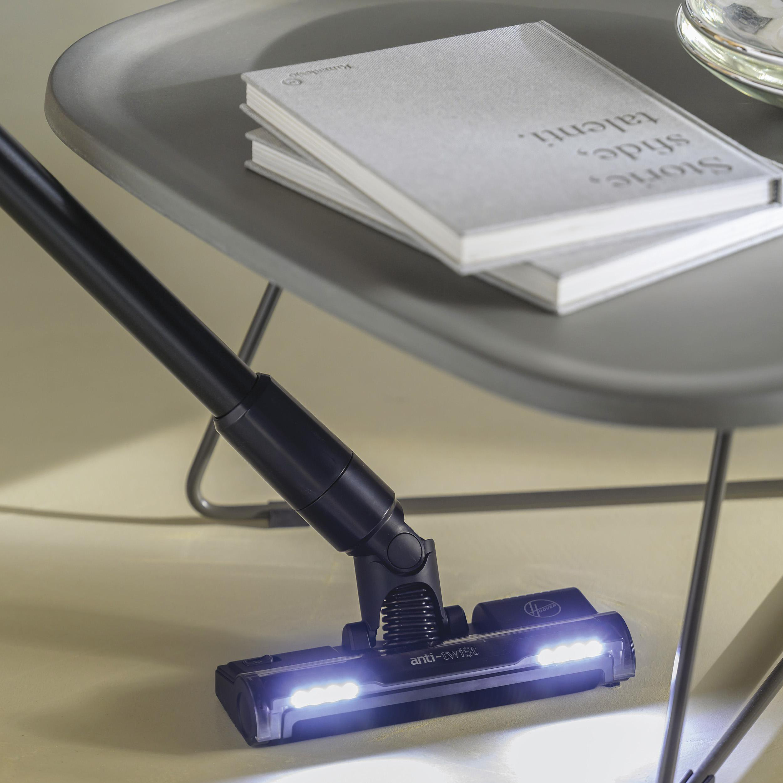 Staubsaugerkopf mit Lichtern. Zwei Bücher auf einem grauen Tisch im Hintergrund.