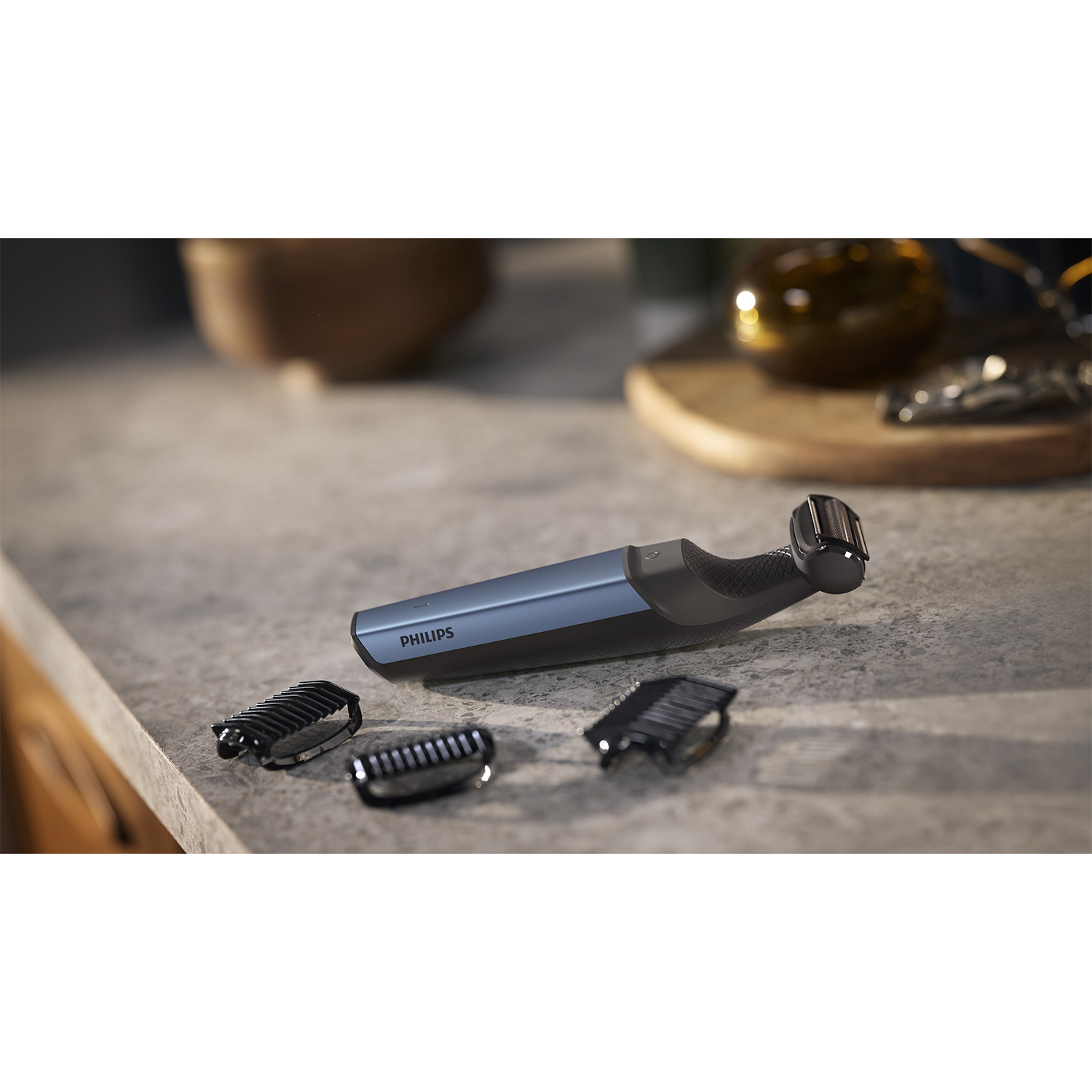 Un rasoio Philips nero e blu e tre accessori su una superficie grigia.