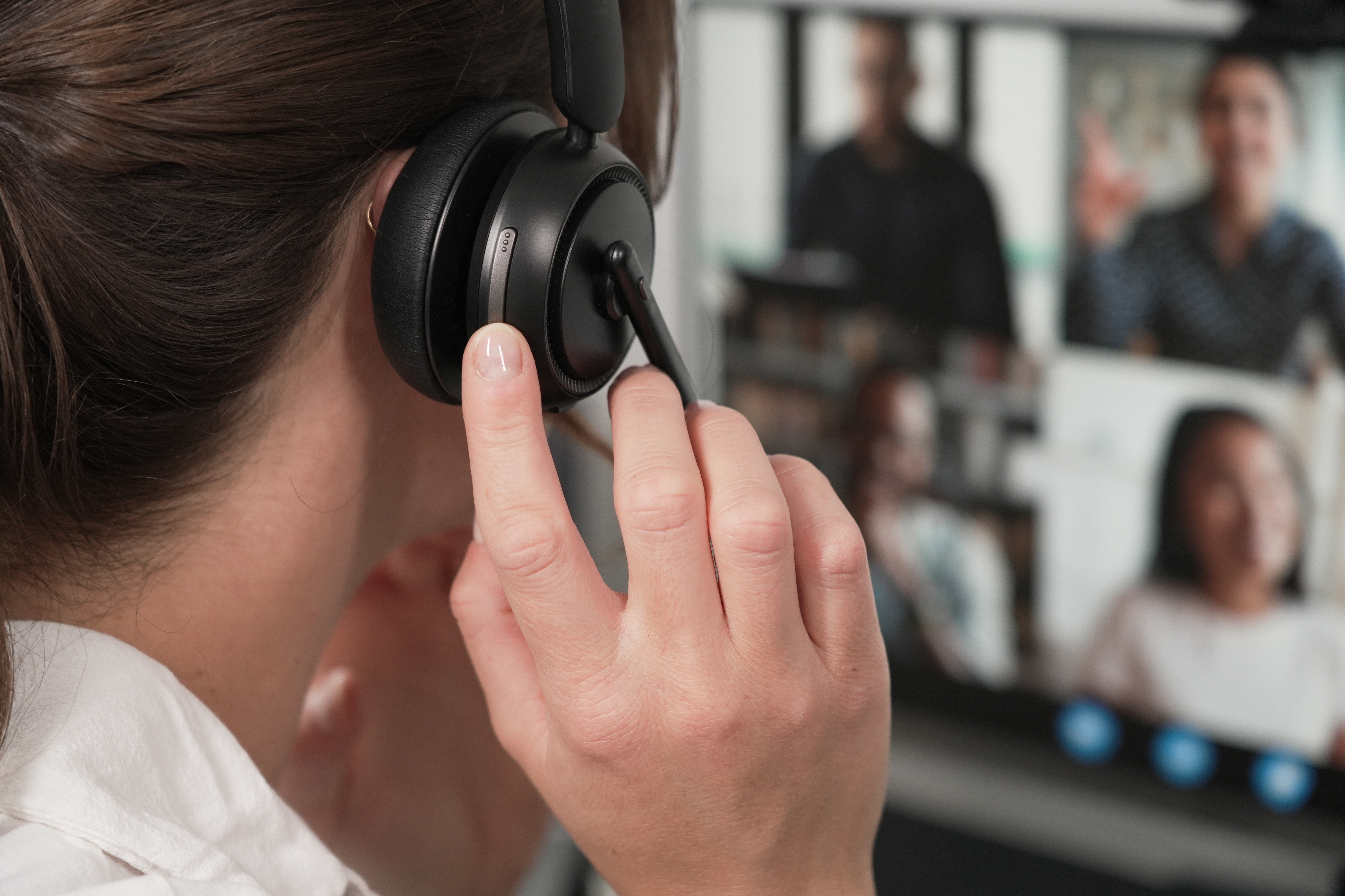 Eine Frau mit Headset nimmt an einer Videokonferenz auf einem Computerbildschirm teil.